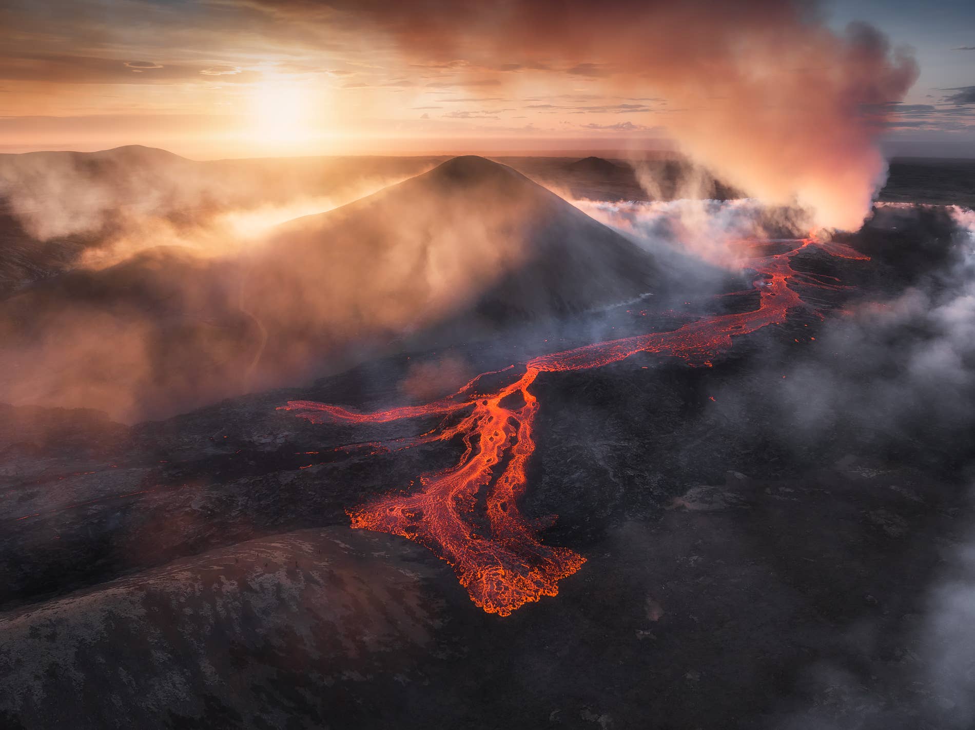Molten lava channels glowing below Litli-Hrútur at sunset on the Reykjanes Peninsula.