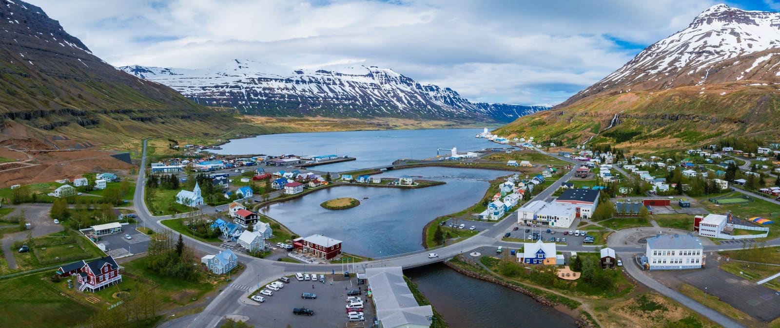 Aerial view of Seyðisfjörður with the fjord, town, and surrounding mountains.