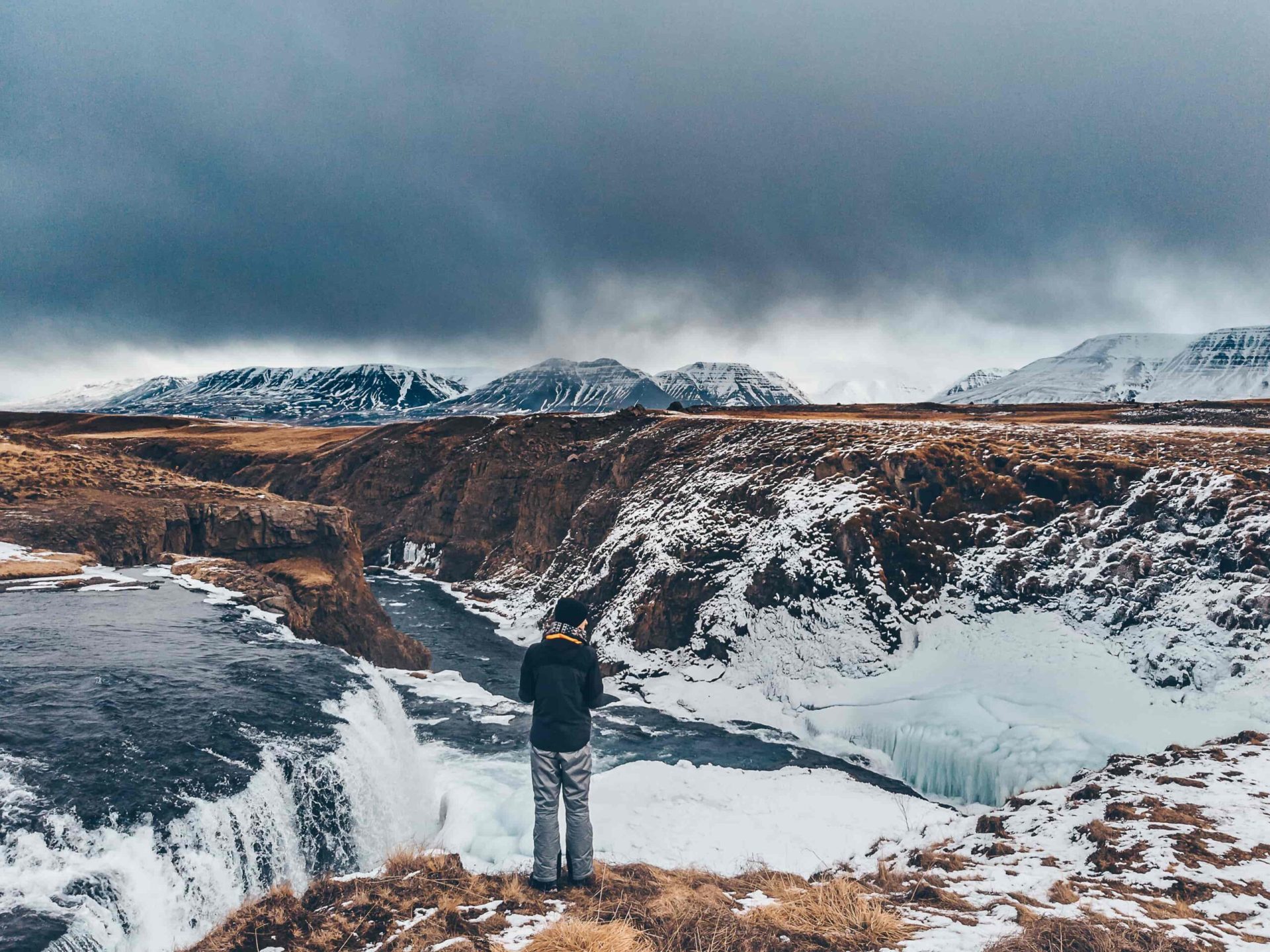 Visitor looking over snowy Reykjafoss and the surrounding Skagafjordur river landscape.