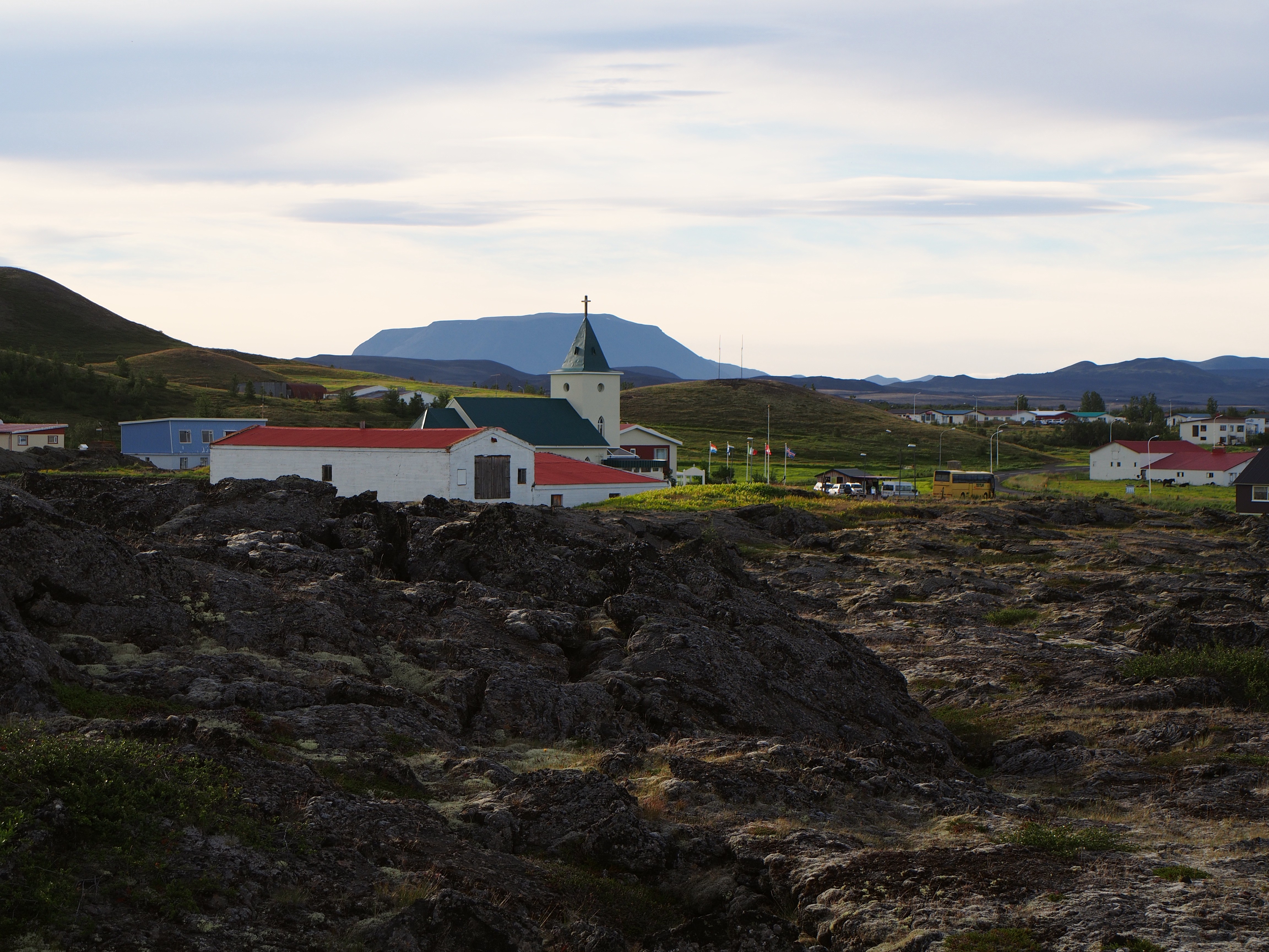 Lava fields around Reykjahlíð with the village visible as a small settlement beyond the dark foreground.