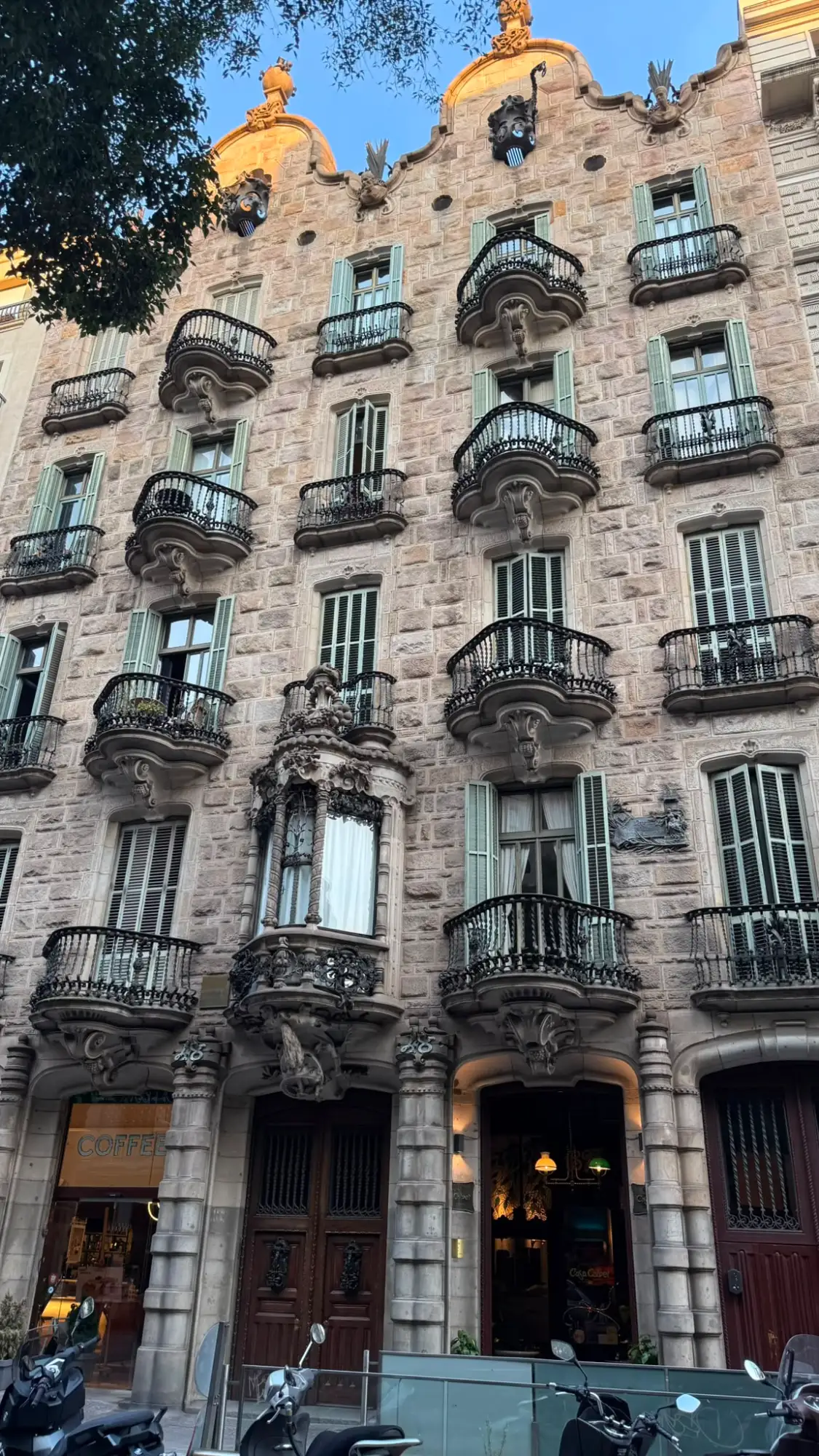 The stone facade of Gaudí's Casa Calvet in Barcelona, with ornate wrought-iron balconies and sculptural details.