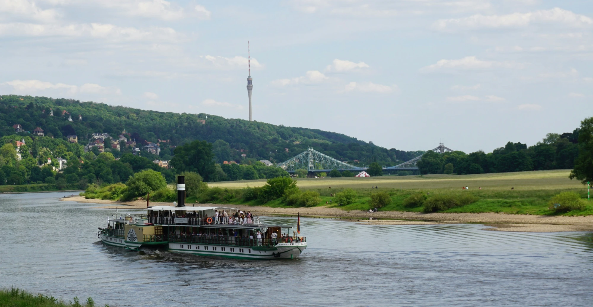 A paddle steamer on the Elbe river in Dresden, with the Blue Wonder bridge and TV tower in the background.
