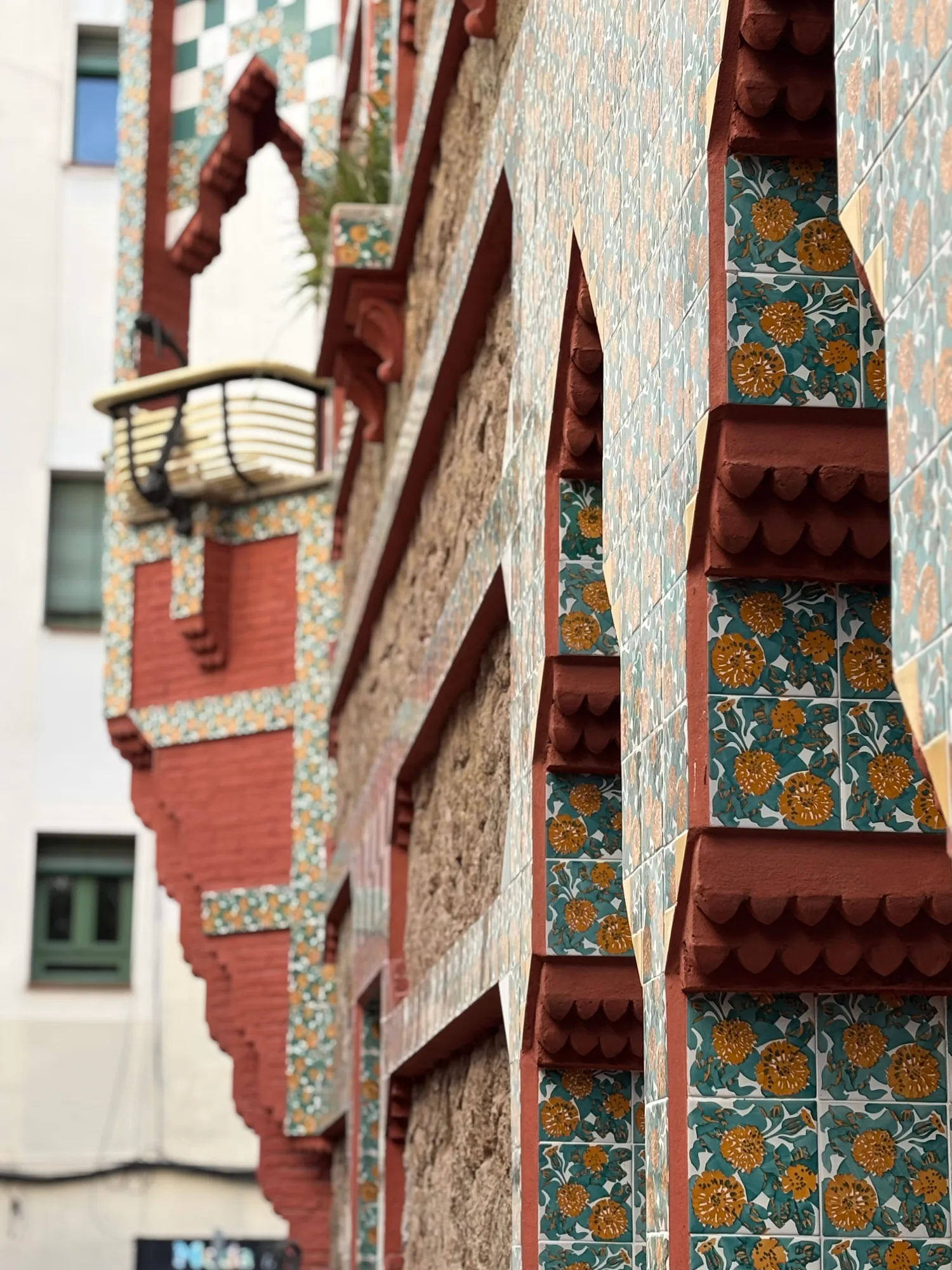 Close-up of the Casa Vicens facade, showing Moorish-style arches and colourful floral marigold tiles.