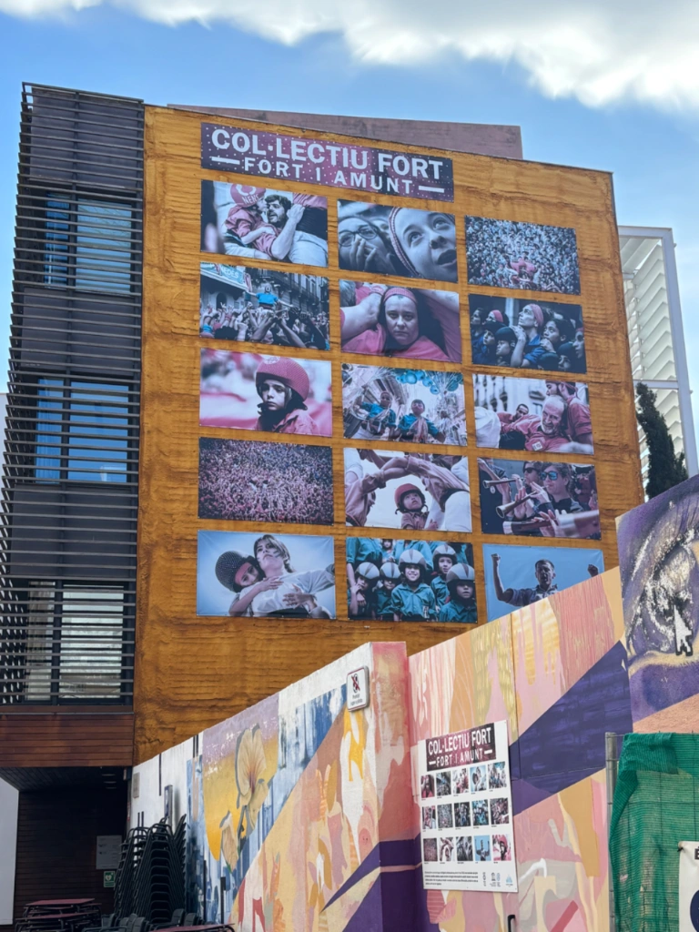 Building facade displaying a photo exhibition by Col·lectiu Fort featuring Catalan human towers.