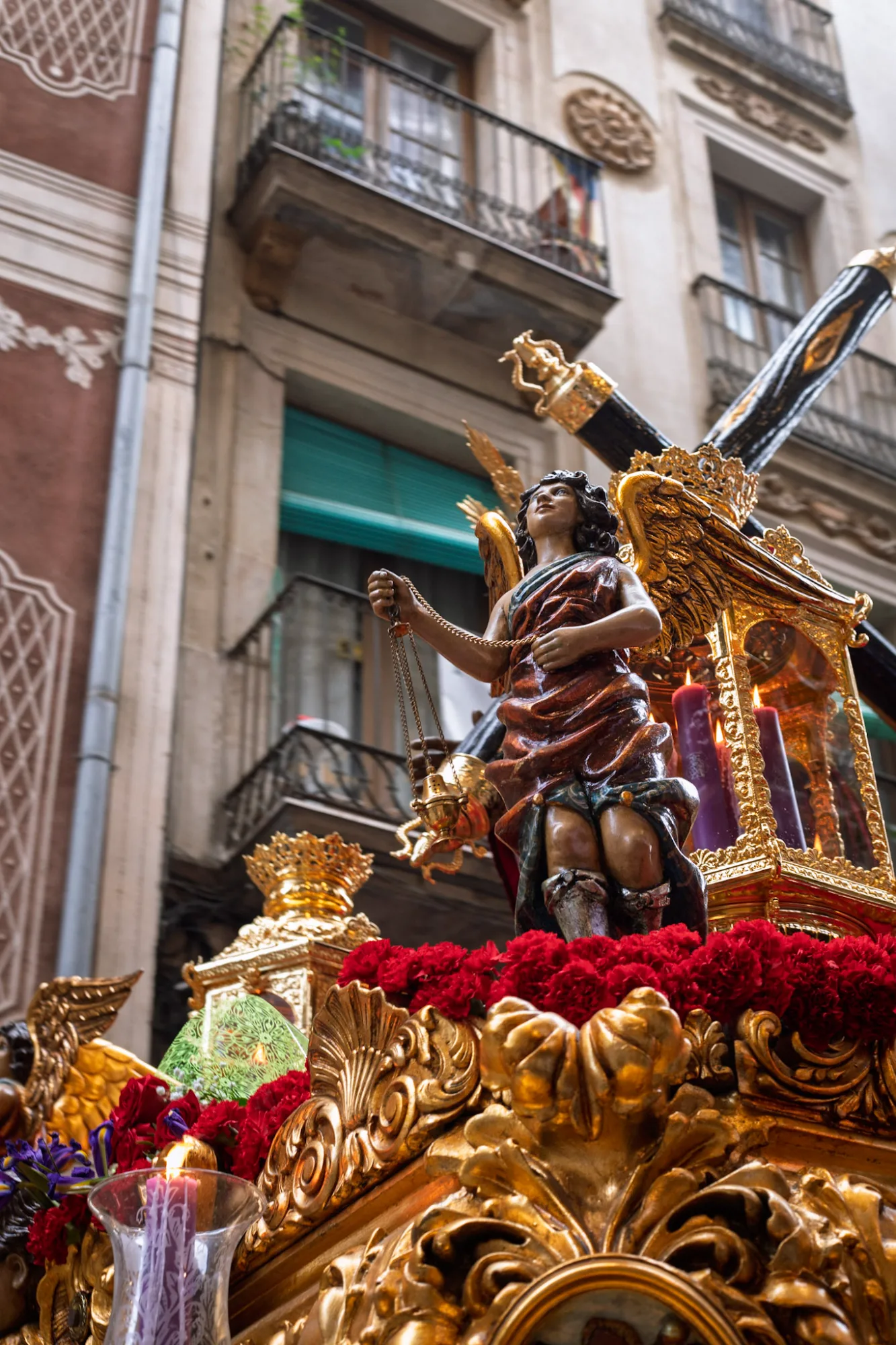 Ornate golden float with a statue of Jesus during a Holy Week procession in Barcelona, surrounded by a crowd.
