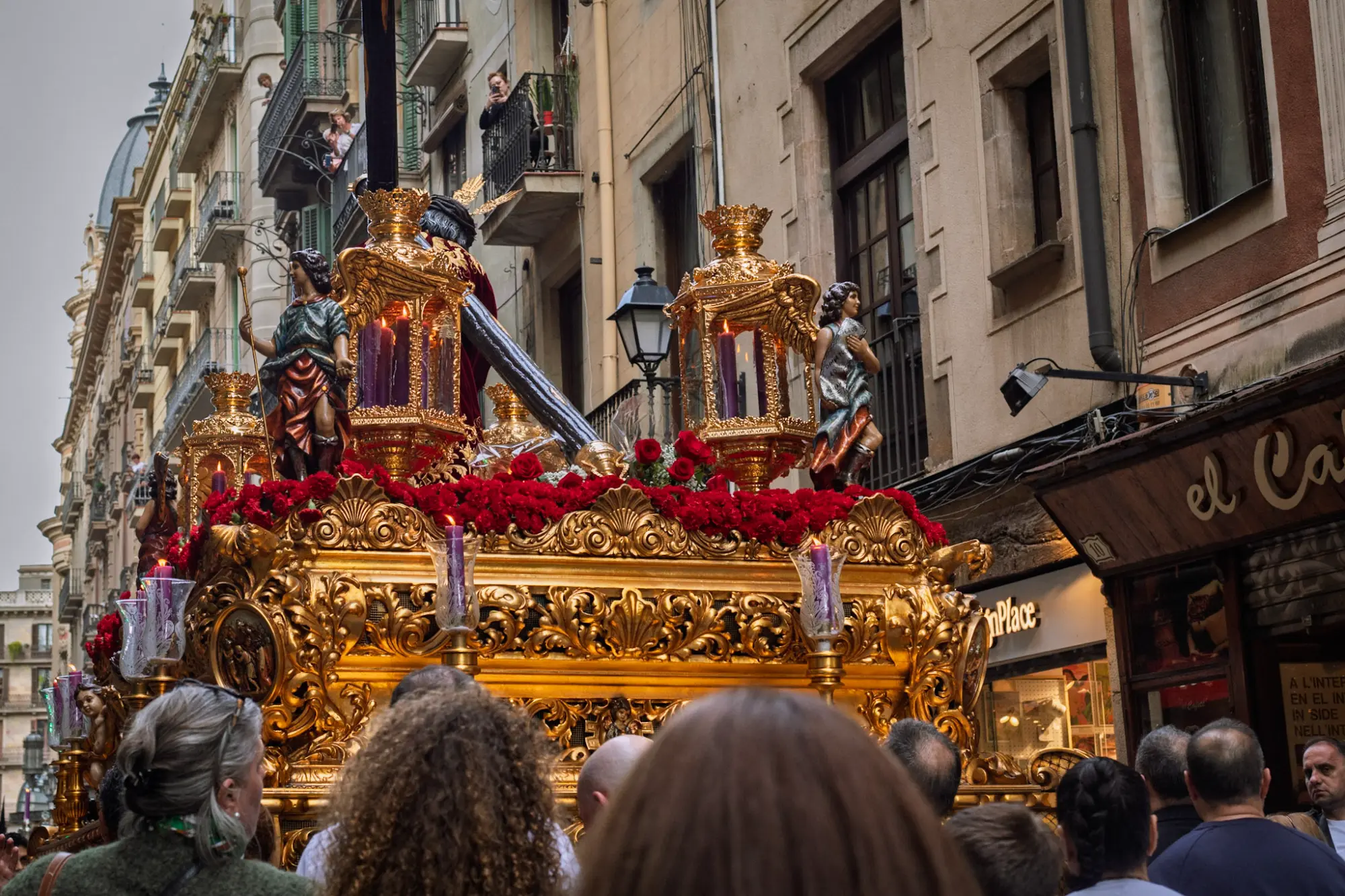 Ornate golden float with a statue of Jesus during a Holy Week procession in Barcelona, surrounded by a crowd.