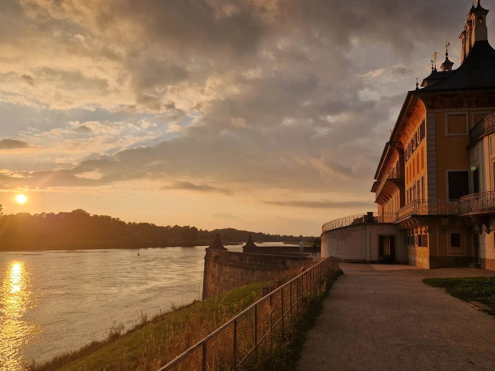 Pillnitz Palace on the bank of the Elbe river in Dresden during a warm, golden sunset.