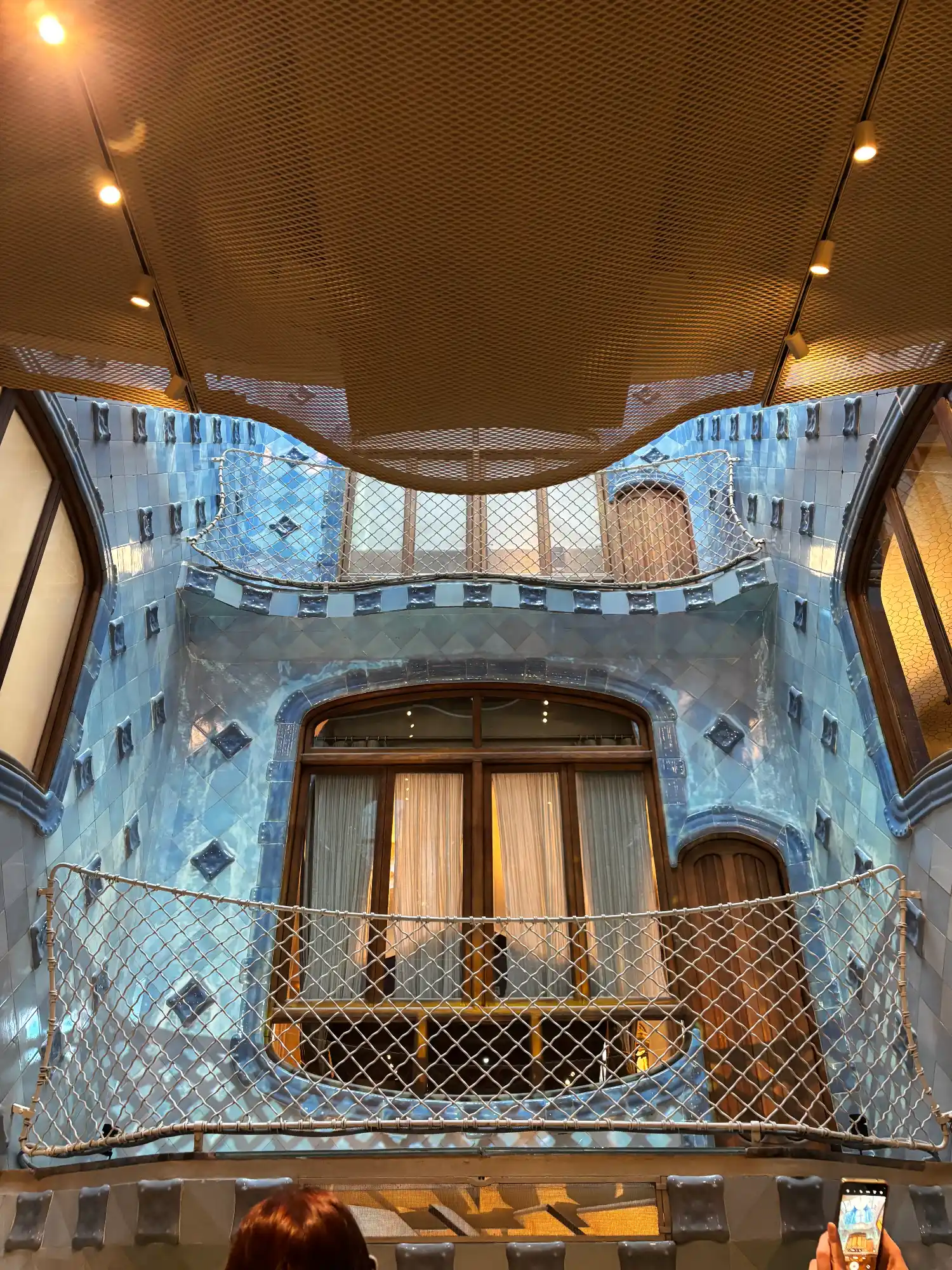 The inner courtyard of Casa Batlló, showing its famous blue tiles and wavy balconies designed to reflect light.