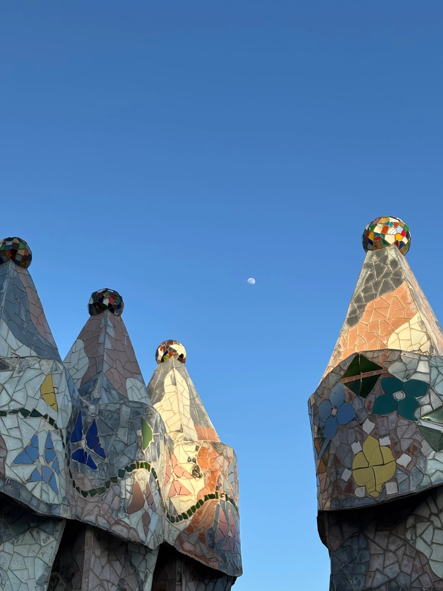 Gaudí's whimsical rooftop chimneys of Casa Batlló against the clear blue sky.
