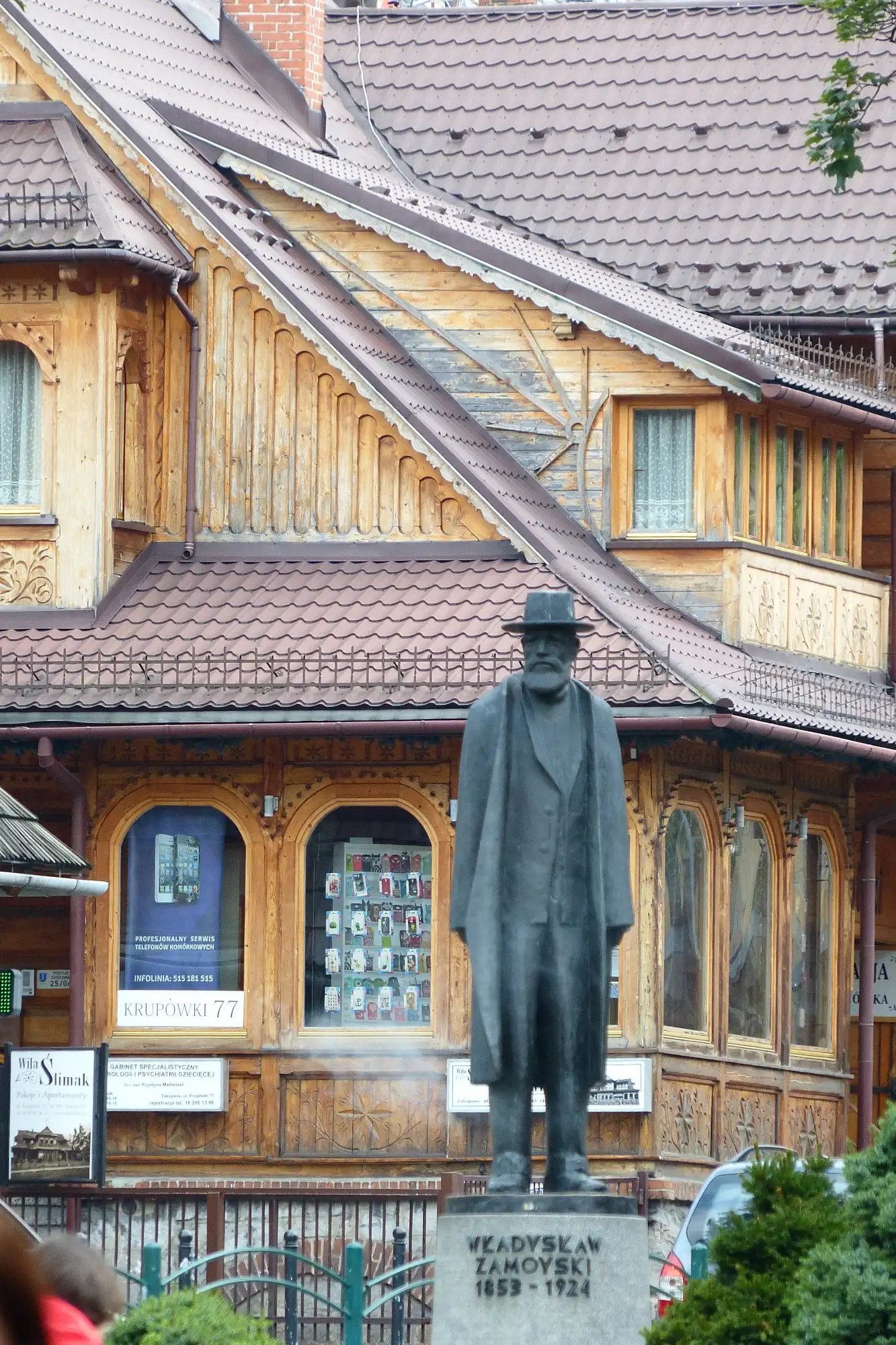 Bronze statue of Władysław Zamoyski in front of an ornate wooden Zakopane-style villa.