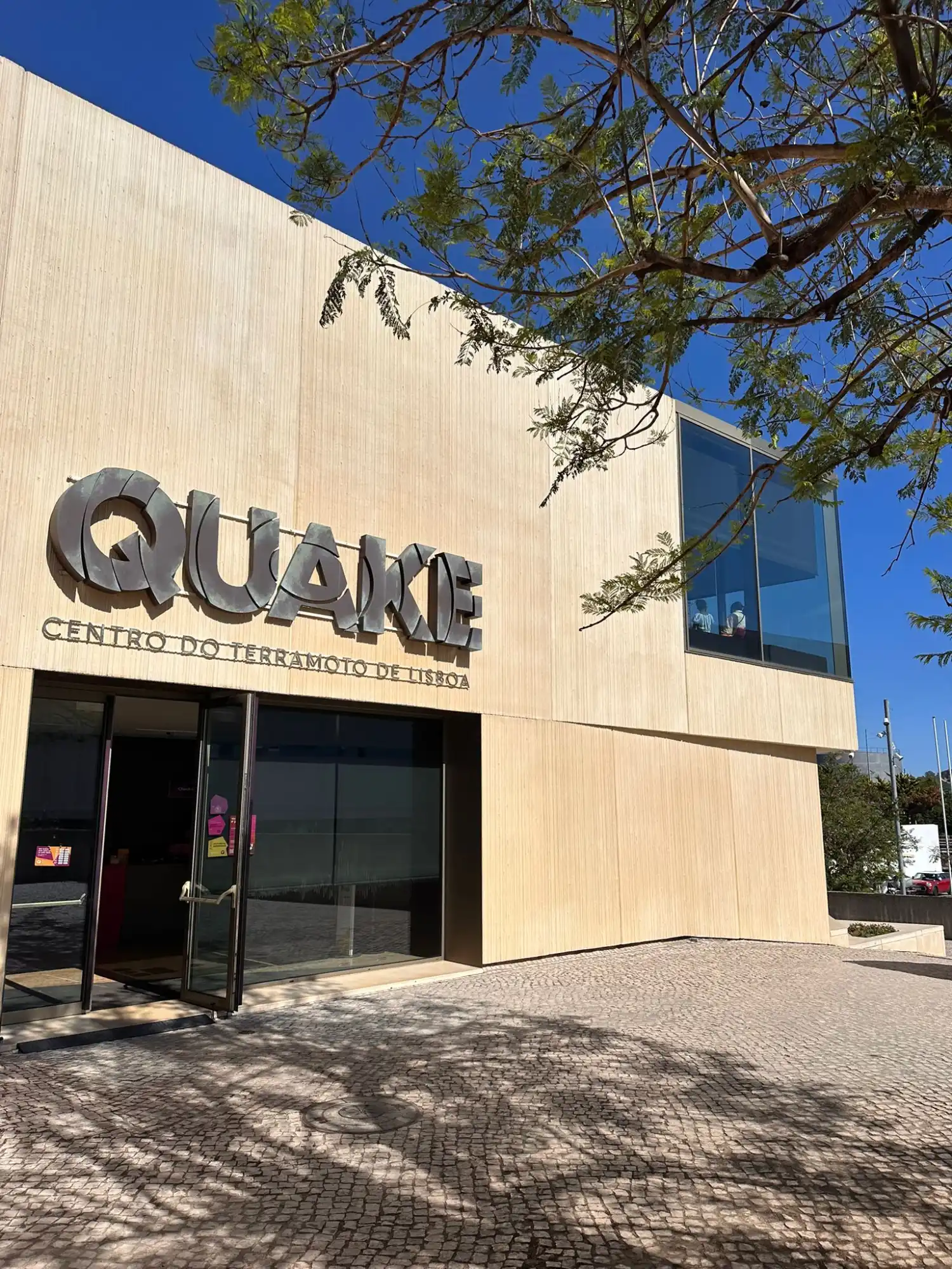 The entrance to the modern Quake Lisbon Earthquake Centre building on a sunny day.