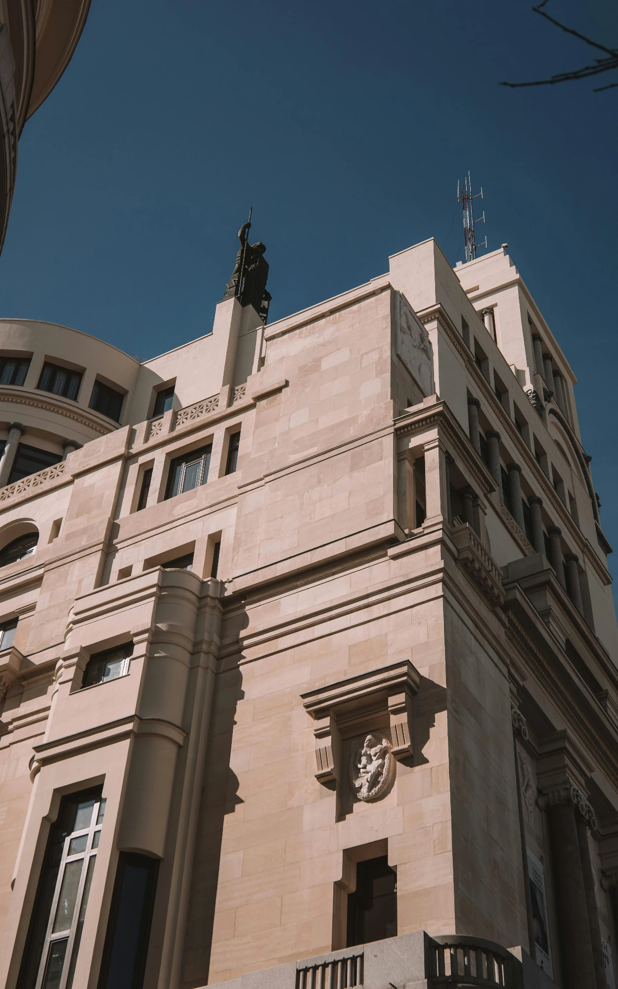 A low-angle view of the Círculo de Bellas Artes building in Madrid, showing its stone facade and rooftop Minerva statue.