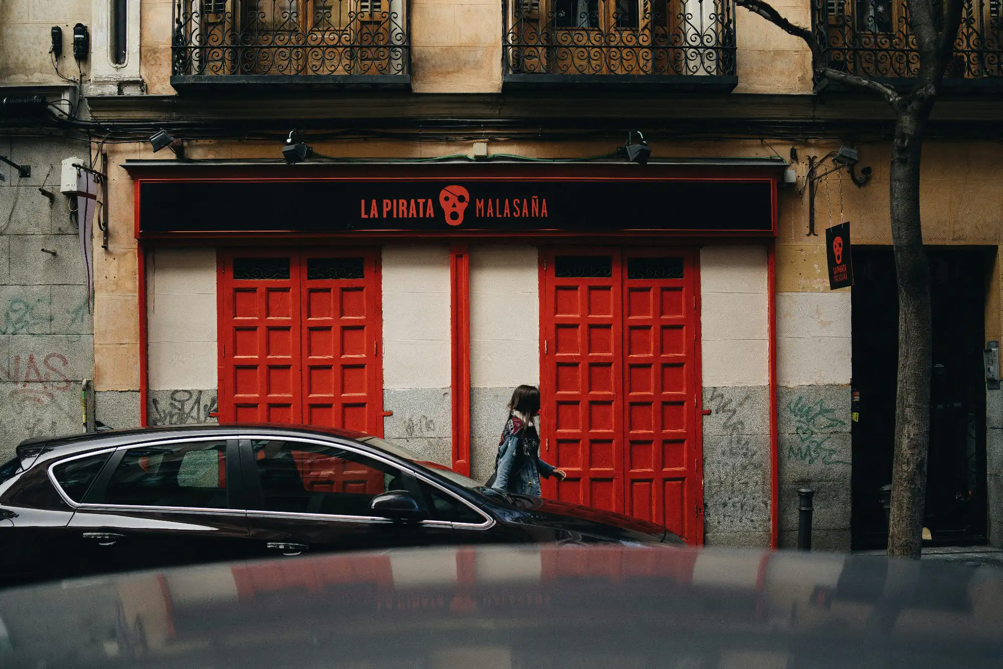 The facade of the La Pirata bar in Malasaña, Madrid, with its bright red doors and black sign above.
