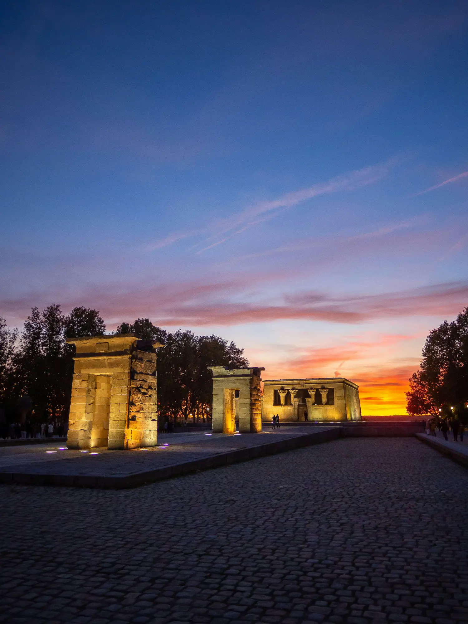 The ancient Egyptian Temple of Debod in Madrid, illuminated with artificial lights during sunset.