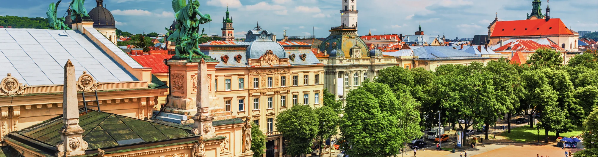 Rynok Square in Lviv at dusk showing historic buildings, illuminated street lamps, and the City Hall on the right.