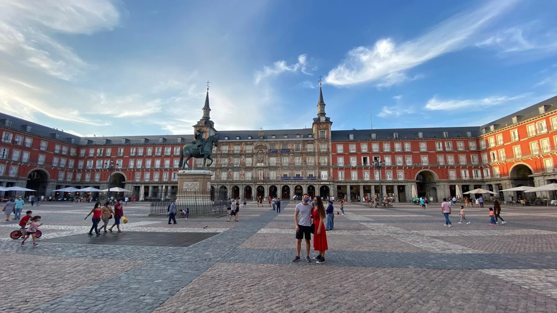 Equestrian statue of Philip III in the center of Madrid's Plaza Mayor, surrounded by red buildings with white windows under a