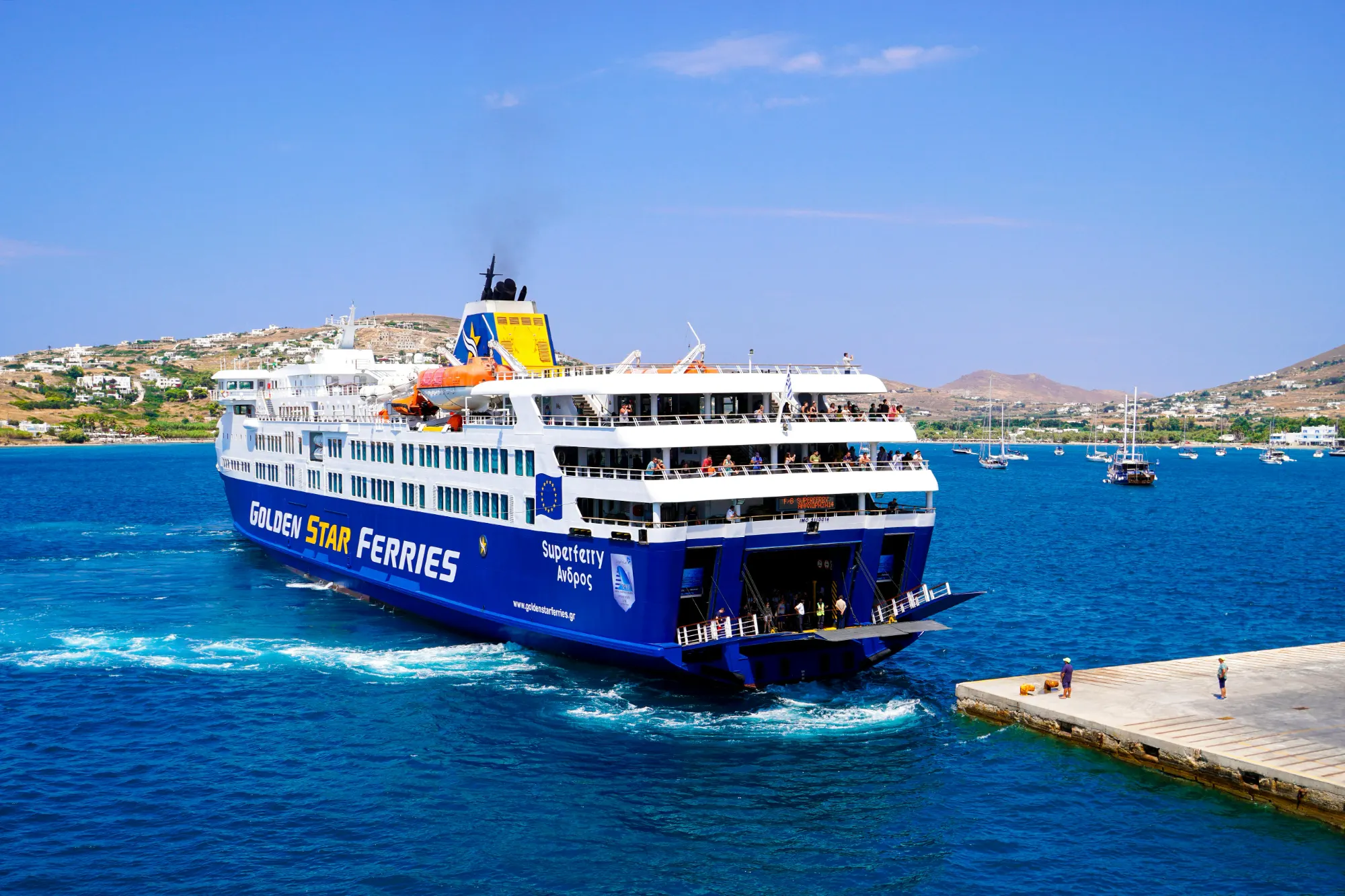 Blau-weiße Passagierfähre von Golden Star Ferries nähert sich einem Betonpier auf einer griechischen Insel.