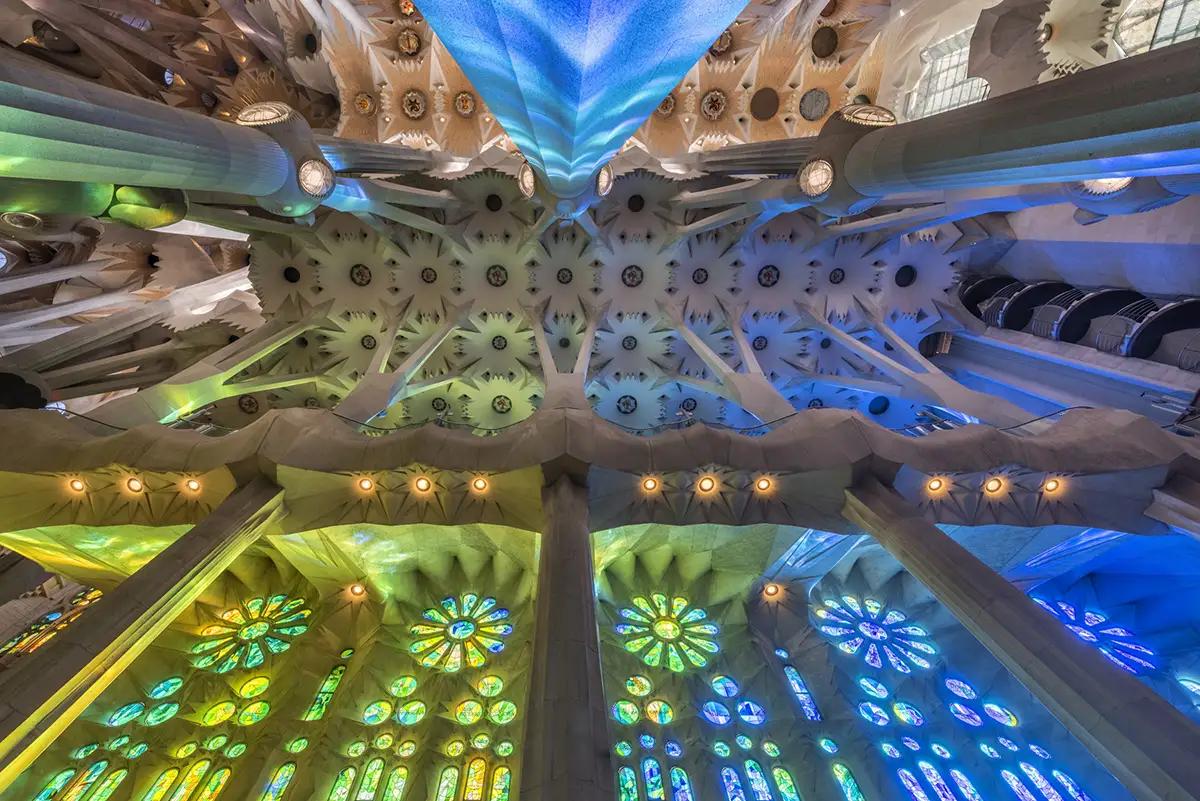 Detailreiche, farbenfrohe Decke und Glasfenster der Sagrada Familia in Barcelona im wechselnden Lichtspiel.