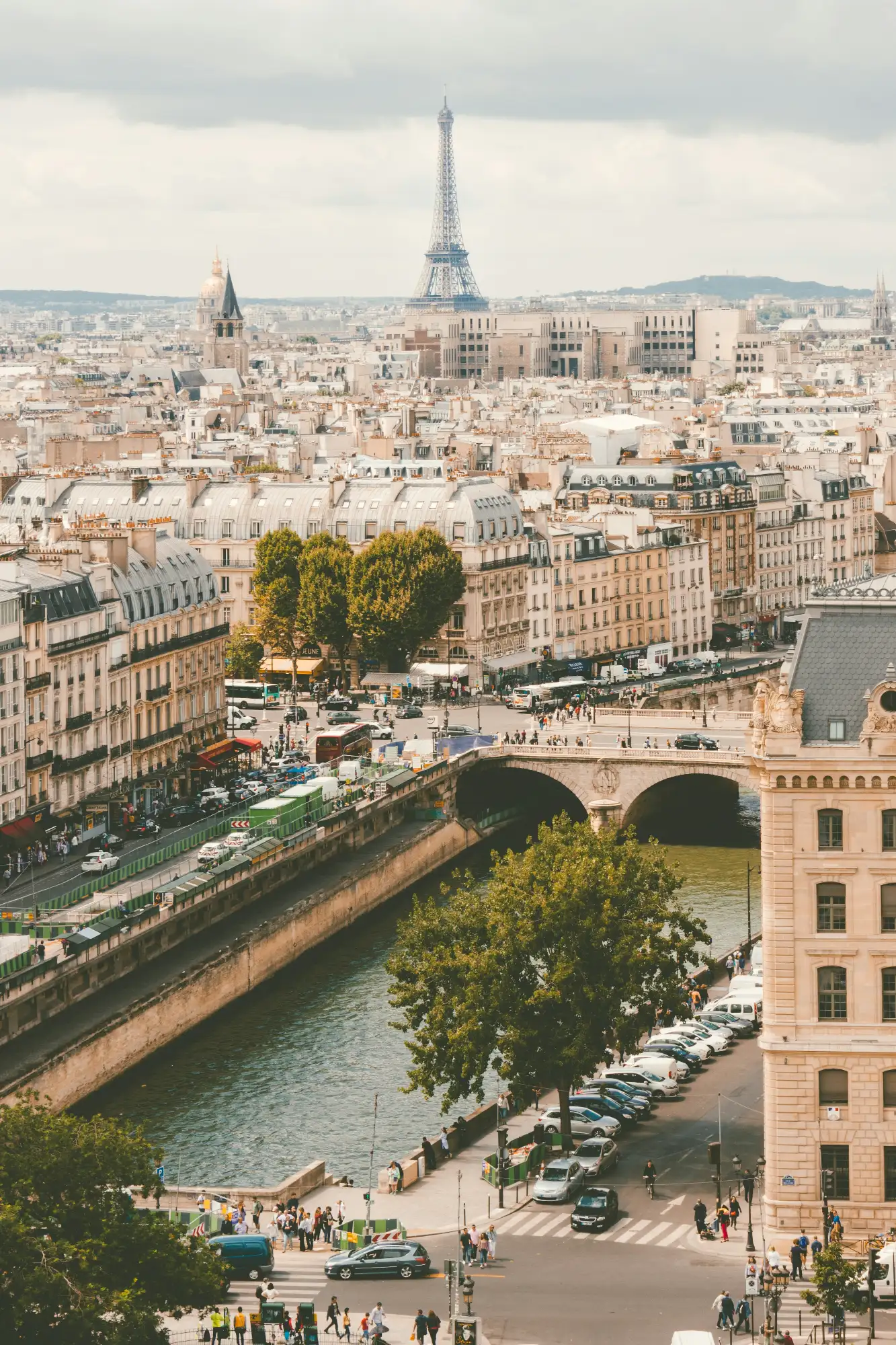 Vista de los tejados de París, el río Sena y la Torre Eiffel a lo lejos en un día nublado.