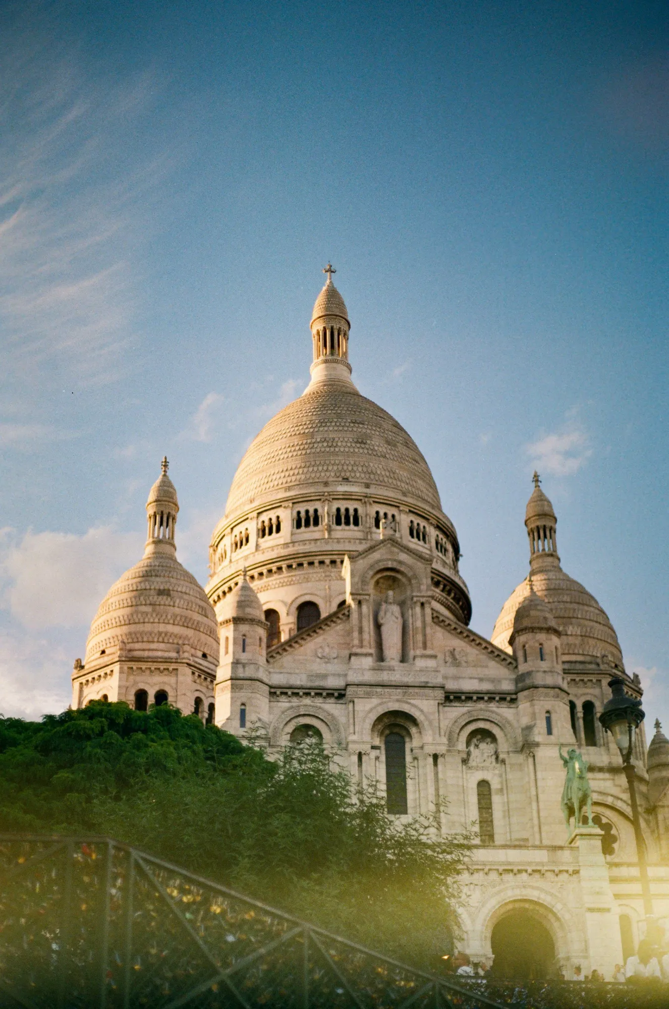 La basílica del Sacré-Cœur con sus cúpulas blancas y su fachada, vista desde abajo al atardecer.