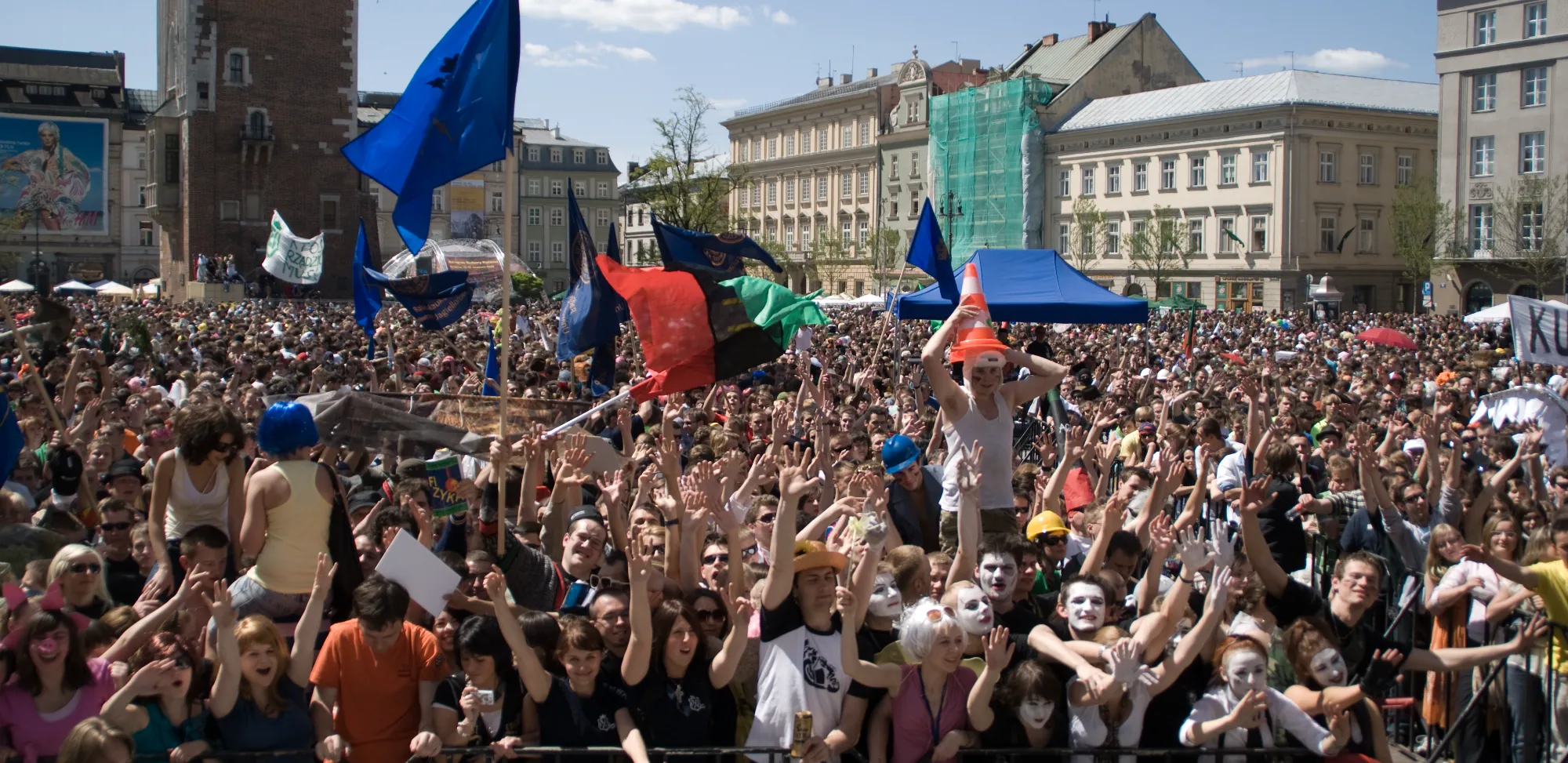 Eine riesige Menschenmenge von Studenten feiert auf dem Hauptmarkt von Krakau, im Hintergrund der Rathausturm.