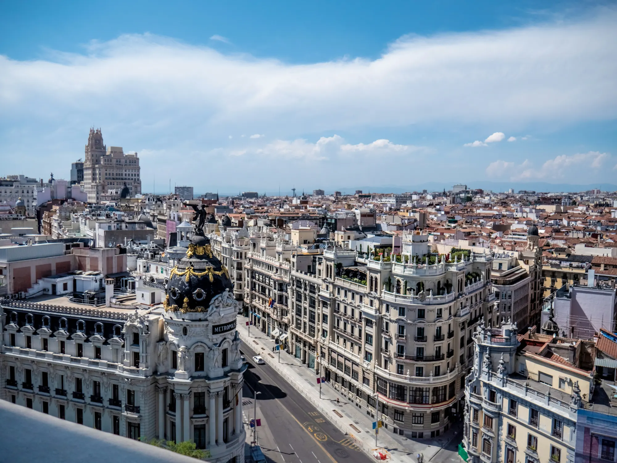 Aerial view of the Metropolis Building and Gran Vía street in Madrid, Spain, under a blue sky.
