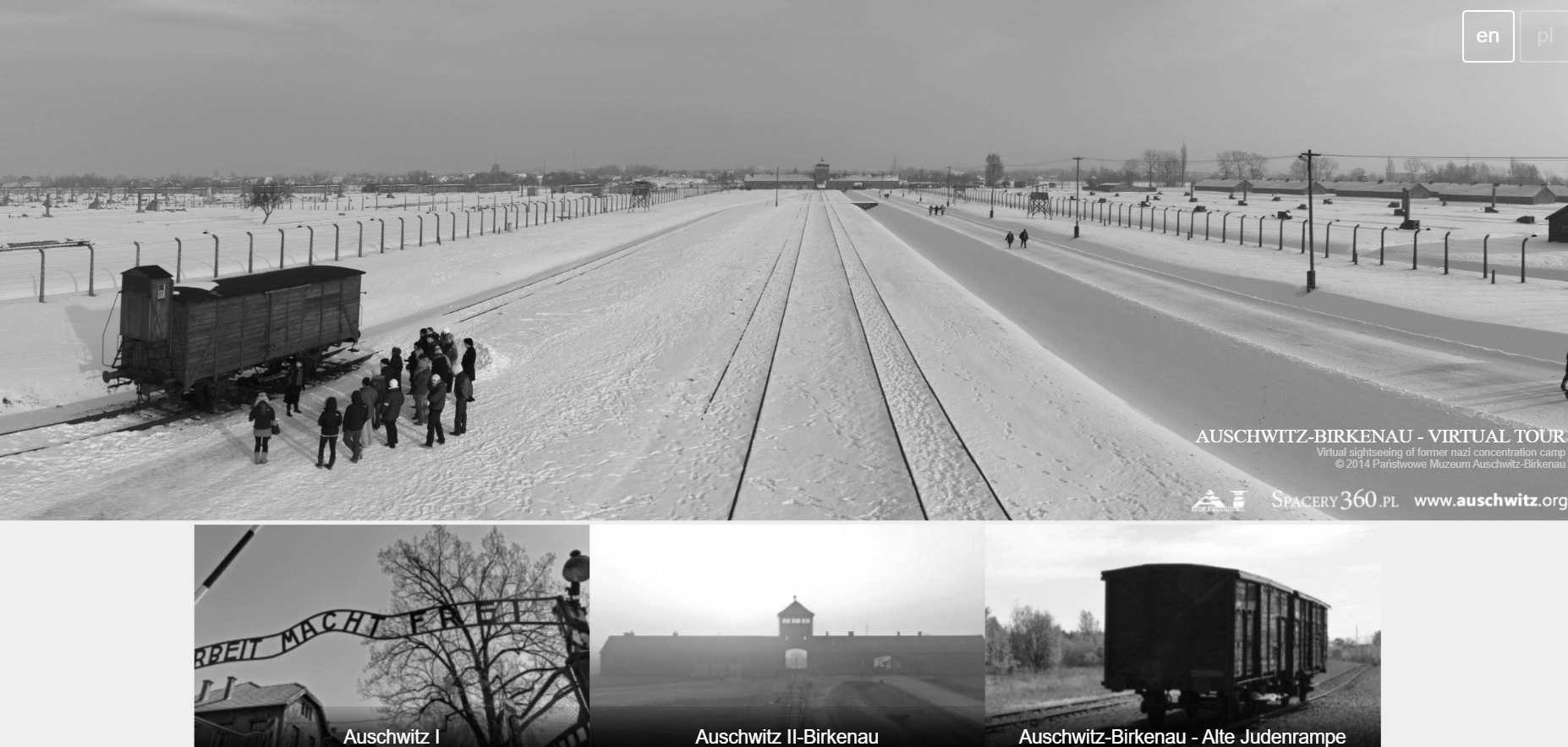 Czarno-biały interfejs wirtualnej wycieczki po Auschwitz-Birkenau ukazujący zimowy widok na obóz, tory i główną bramę.