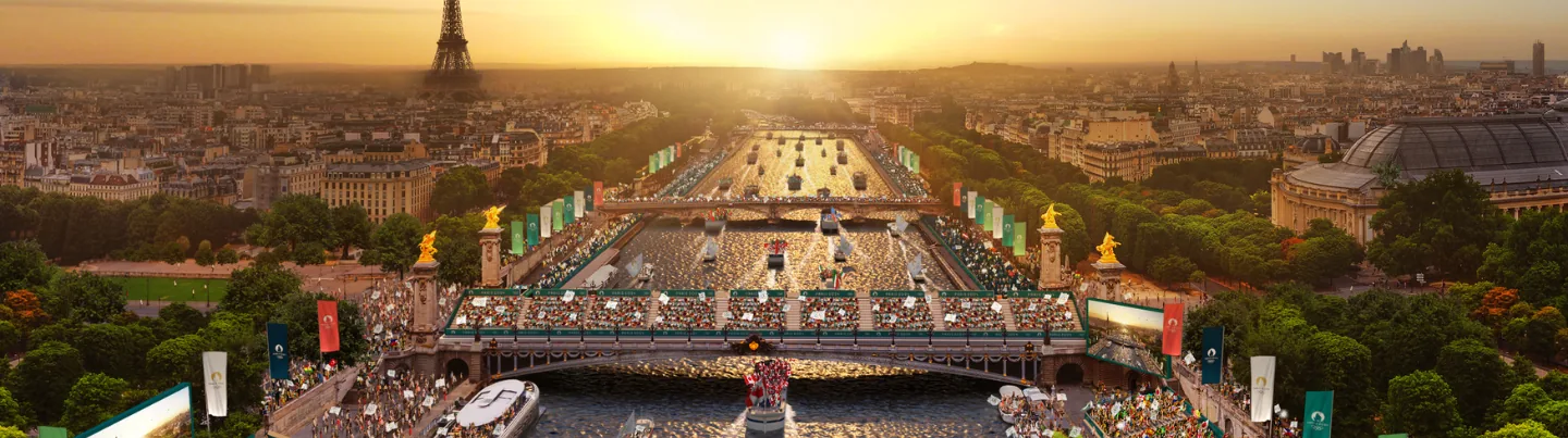 Panoramic sunset view over Paris, with the Seine River lined with spectators, and the Eiffel Tower in the distance.