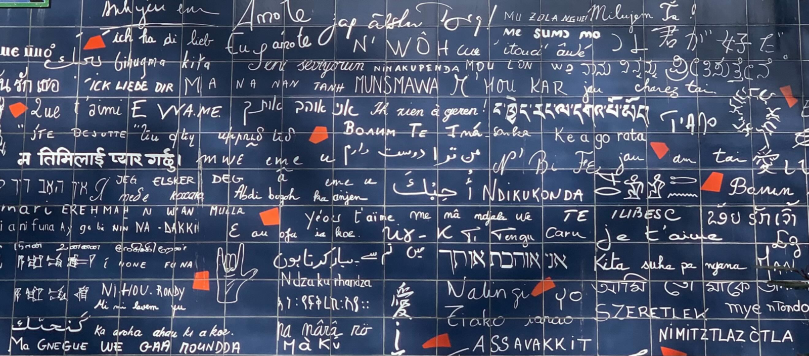 Close-up of blue tiles on the Wall of Love in Paris featuring 'I love you' written in white in multiple languages.