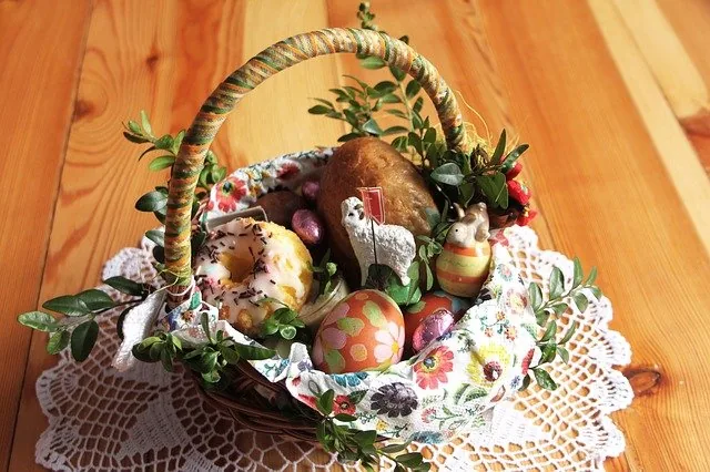 Una tradicional cesta de Pascua polaca (Święconka) con pan, un donut, huevos decorados, chocolate, un cordero y ramas verdes