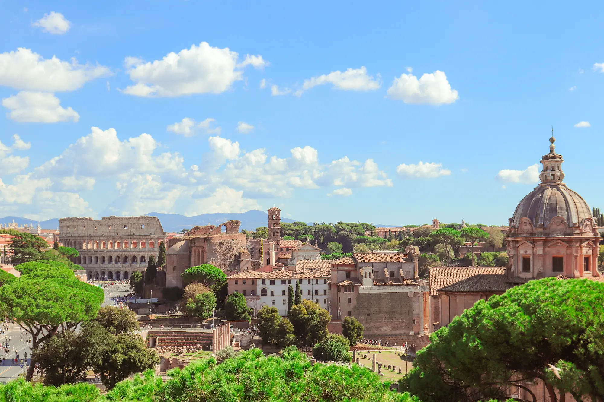 Blick auf das Forum Romanum und das Kolosseum in Rom unter einem blauen Himmel mit Wolken, von einem hohen Standpunkt aus ...
