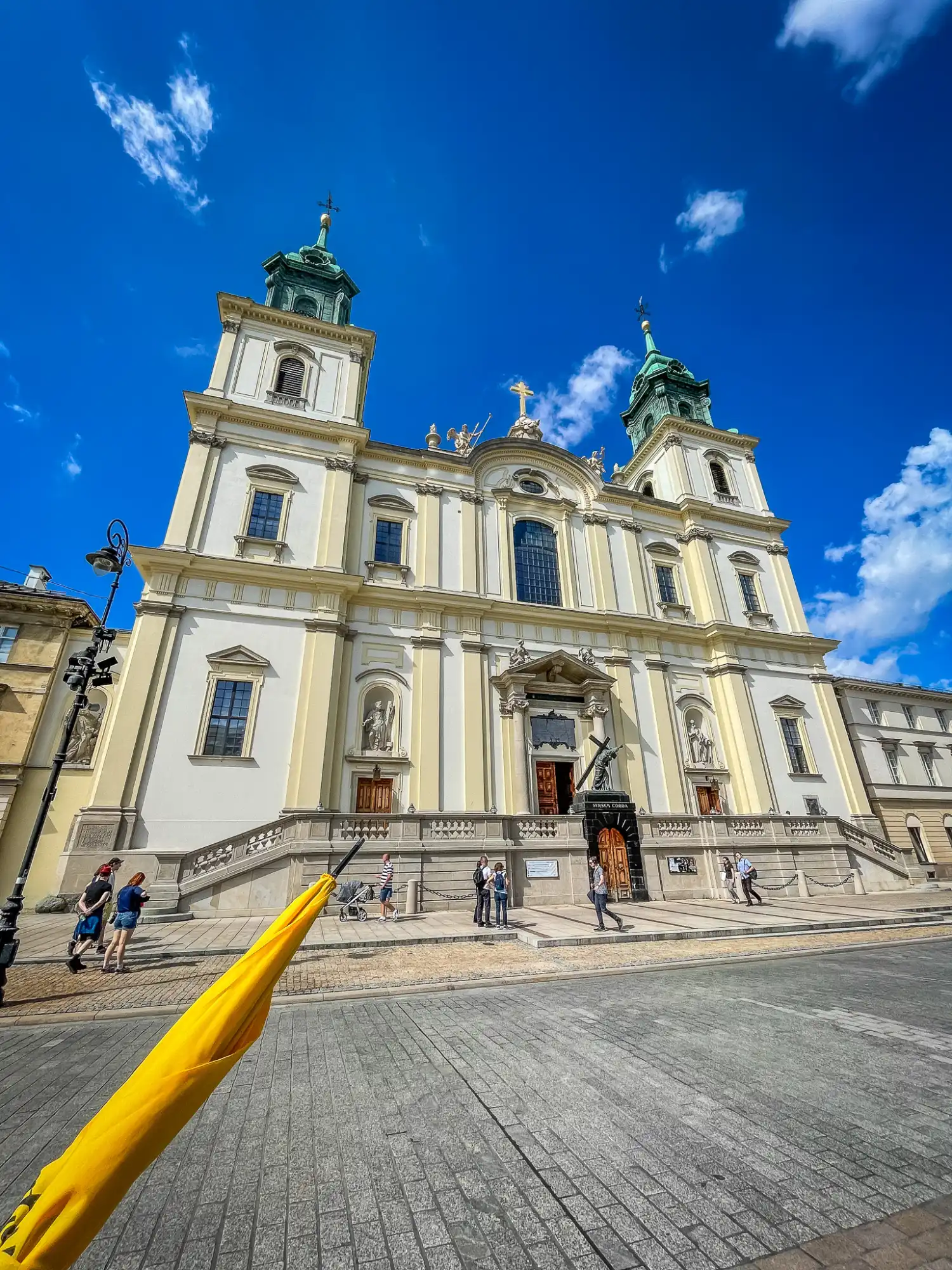 The neoclassical facade of the Carmelite Church in Warsaw against a bright blue sky.