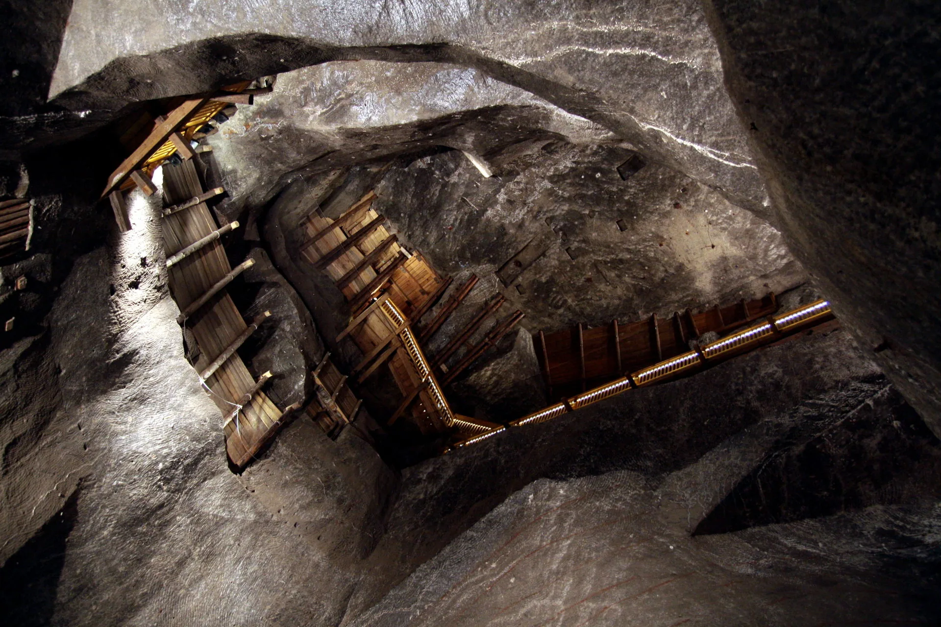 View up into the vast cavern of the Wieliczka Salt Mine, showing wooden structures and illuminated walkways.