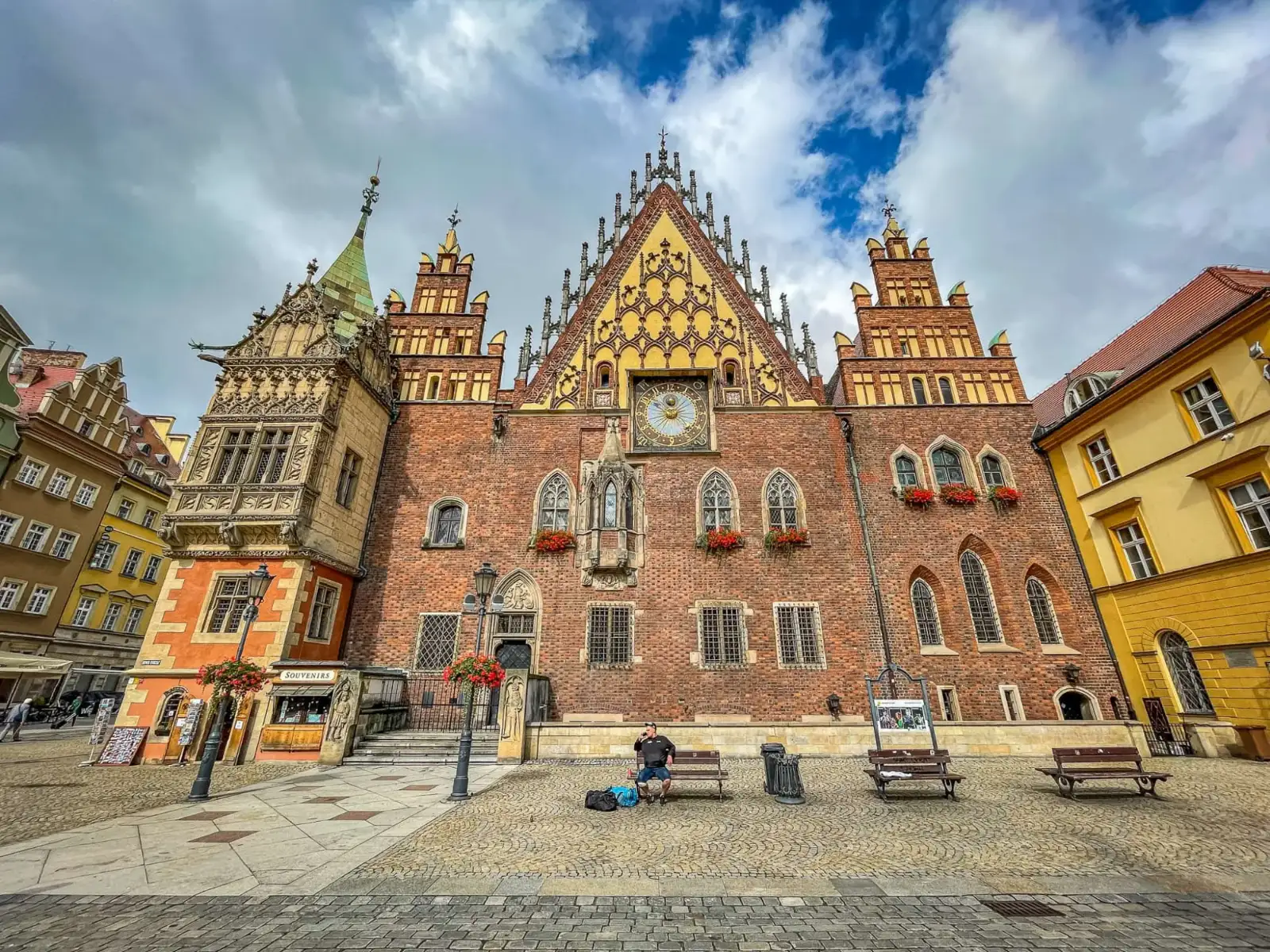 Ratusz we Wrocławiu, duży gotycki ceglany budynek ze zdobionymi szczytami i wieżą zegarową, widziany z Rynku.