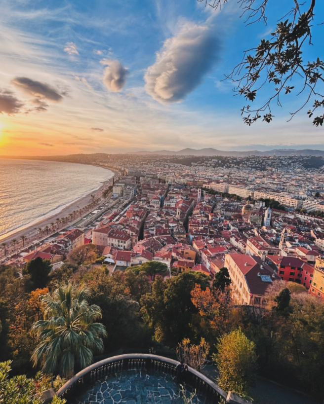 Sunset view over Nice and the Baie des Anges from Castle Hill, featuring the curved coastline and city rooftops.