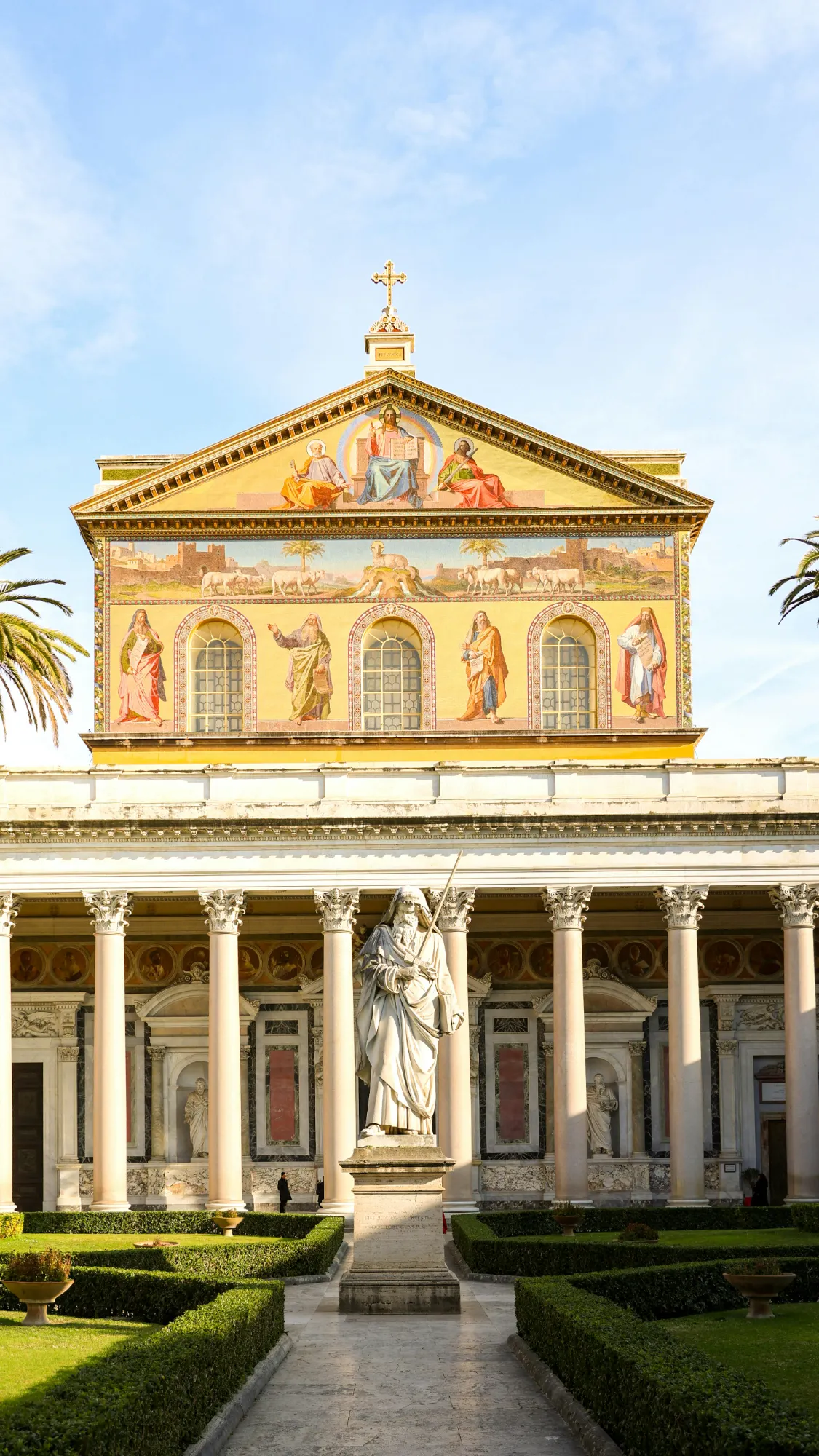 The facade of the Basilica of Saint Paul Outside the Walls in Rome, with a statue of St. Paul in the courtyard.