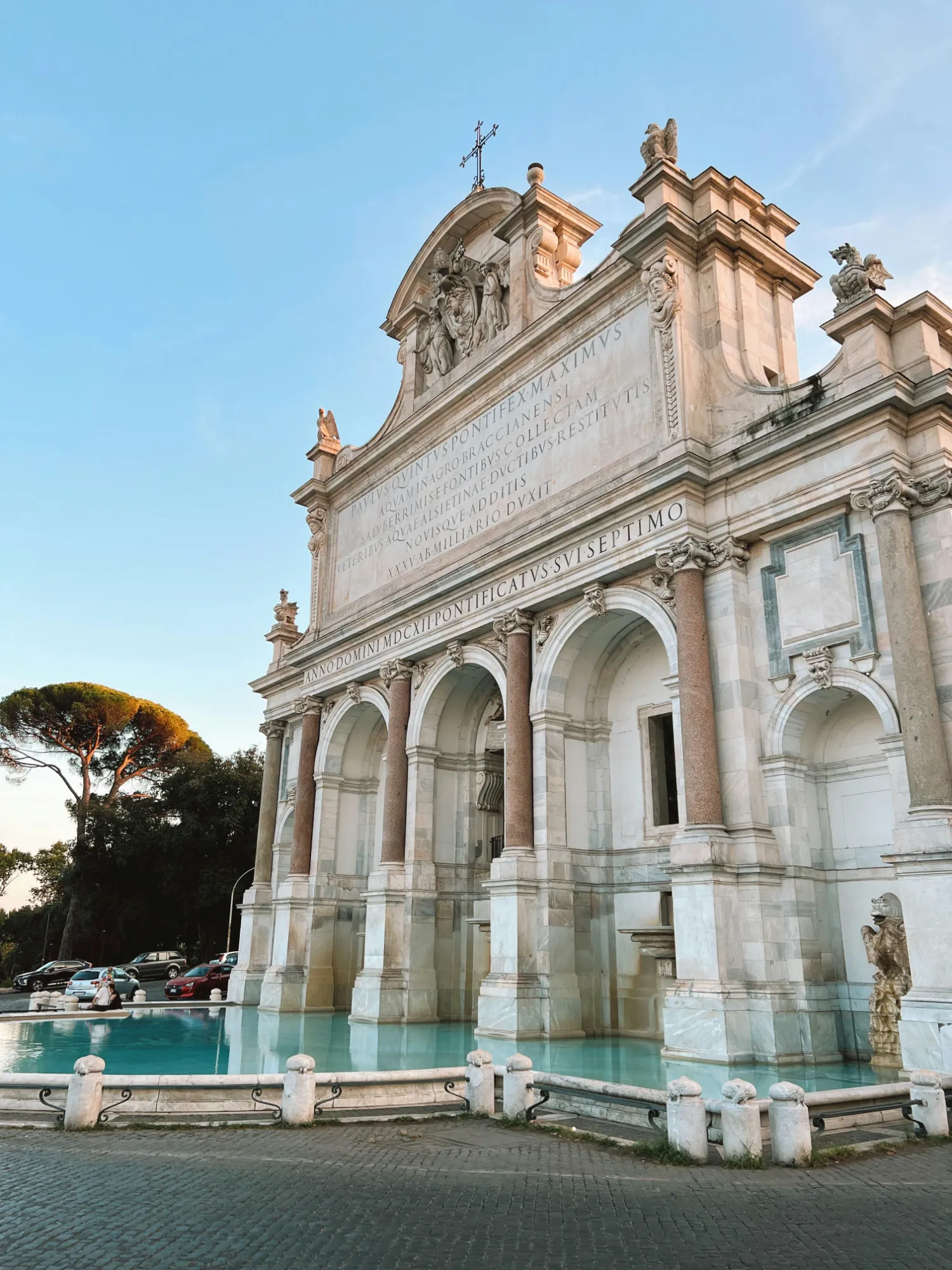 The grand marble Fontana dell'Acqua Paola in Rome at sunset, showing its archways and turquoise water.