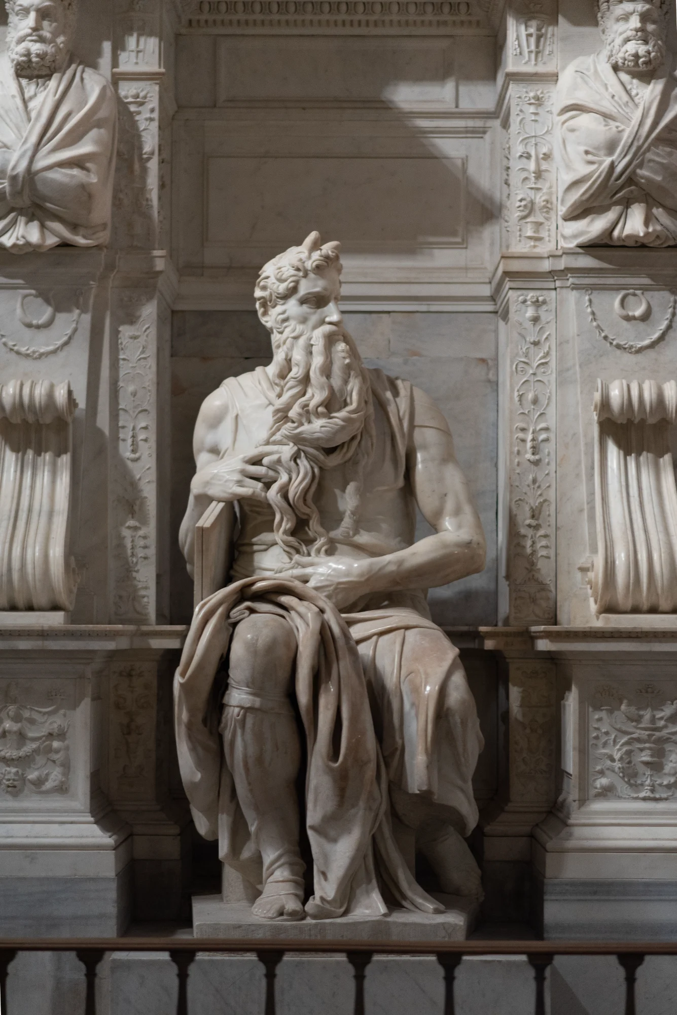 Michelangelo's marble statue of a seated, bearded Moses, holding the tablets and set within an ornate niche.