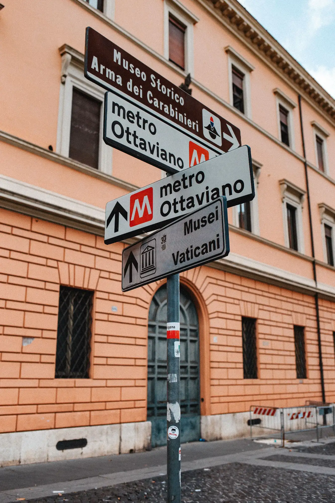 Street signs in Rome pointing to the Ottaviano metro station, the Vatican Museums, and the Museo Storico Arma dei Carabini...
