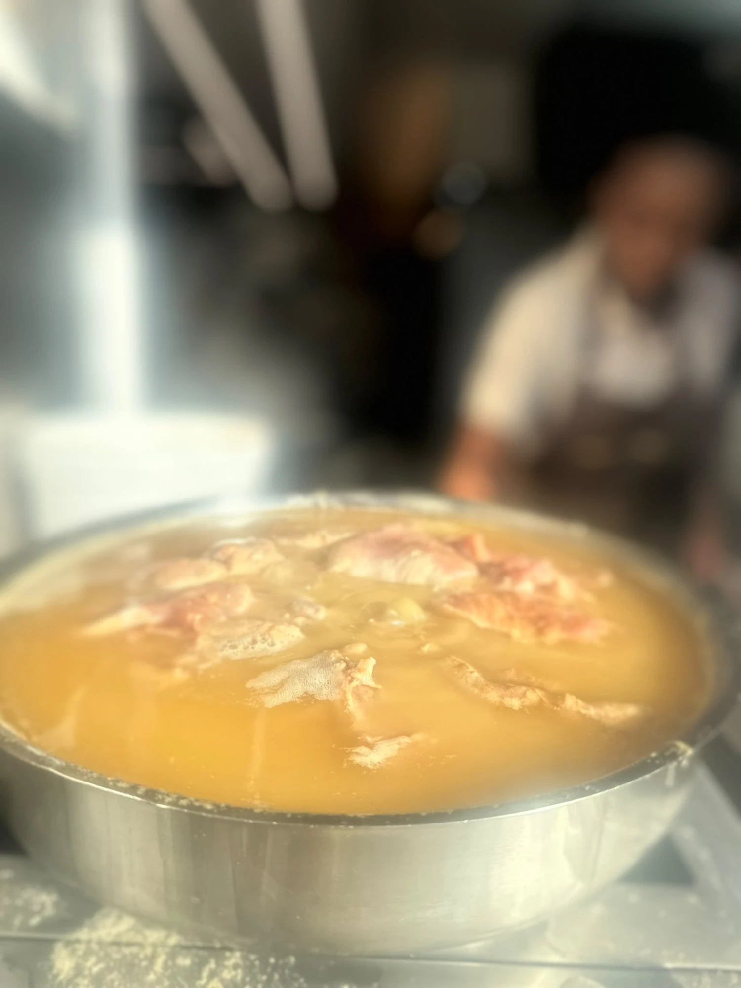 A large metal pot with simmering broth and meat in A casa das bifanas.