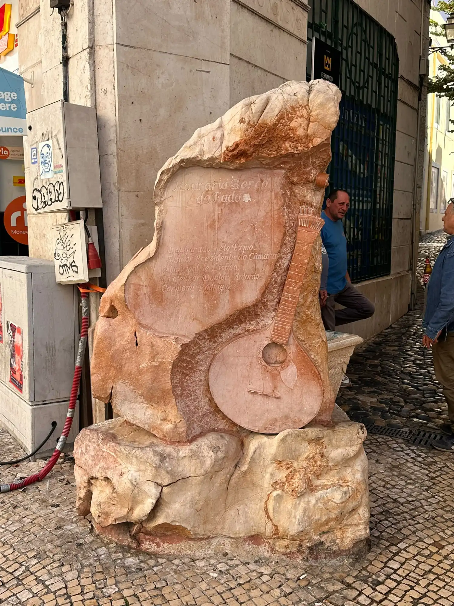 Stone monument carved with a Portuguese guitar and inscription on a street in Mouraria, Lisbon.
