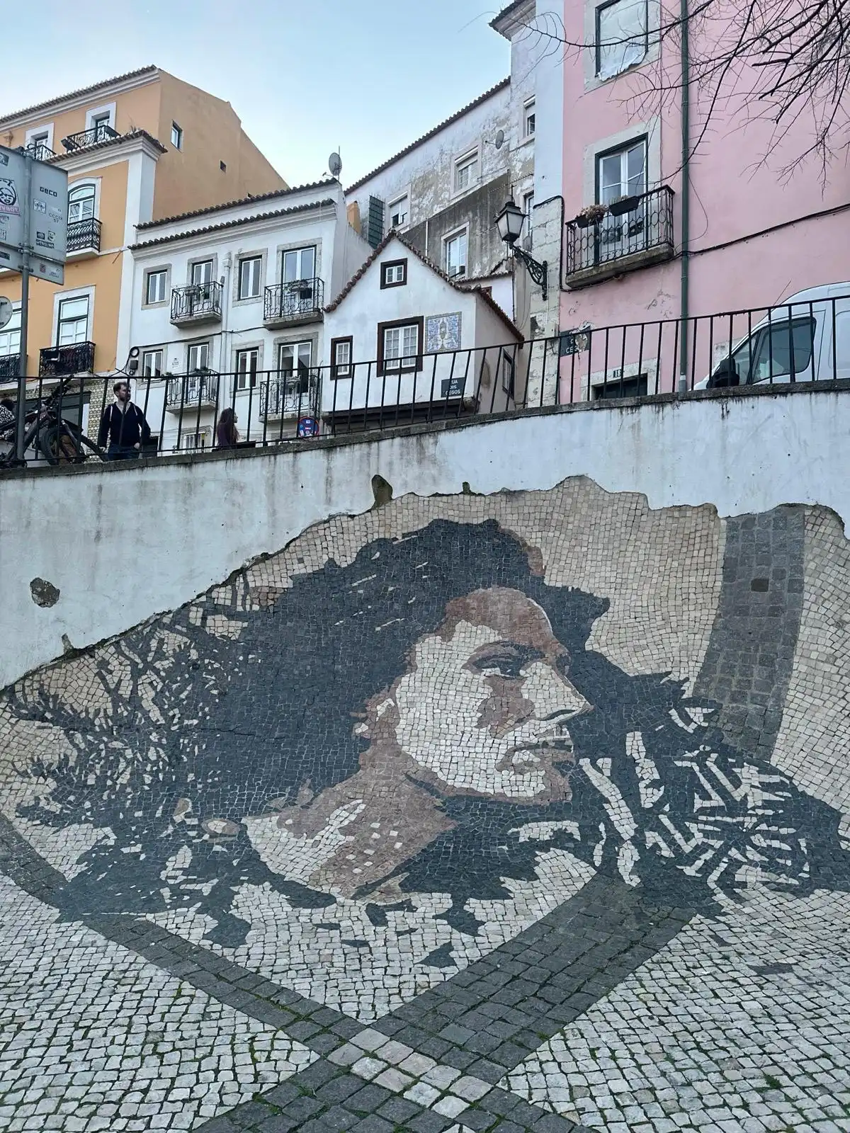 Cobblestone portrait of fado singer Amália Rodrigues on a street wall in Lisbon's Alfama district.