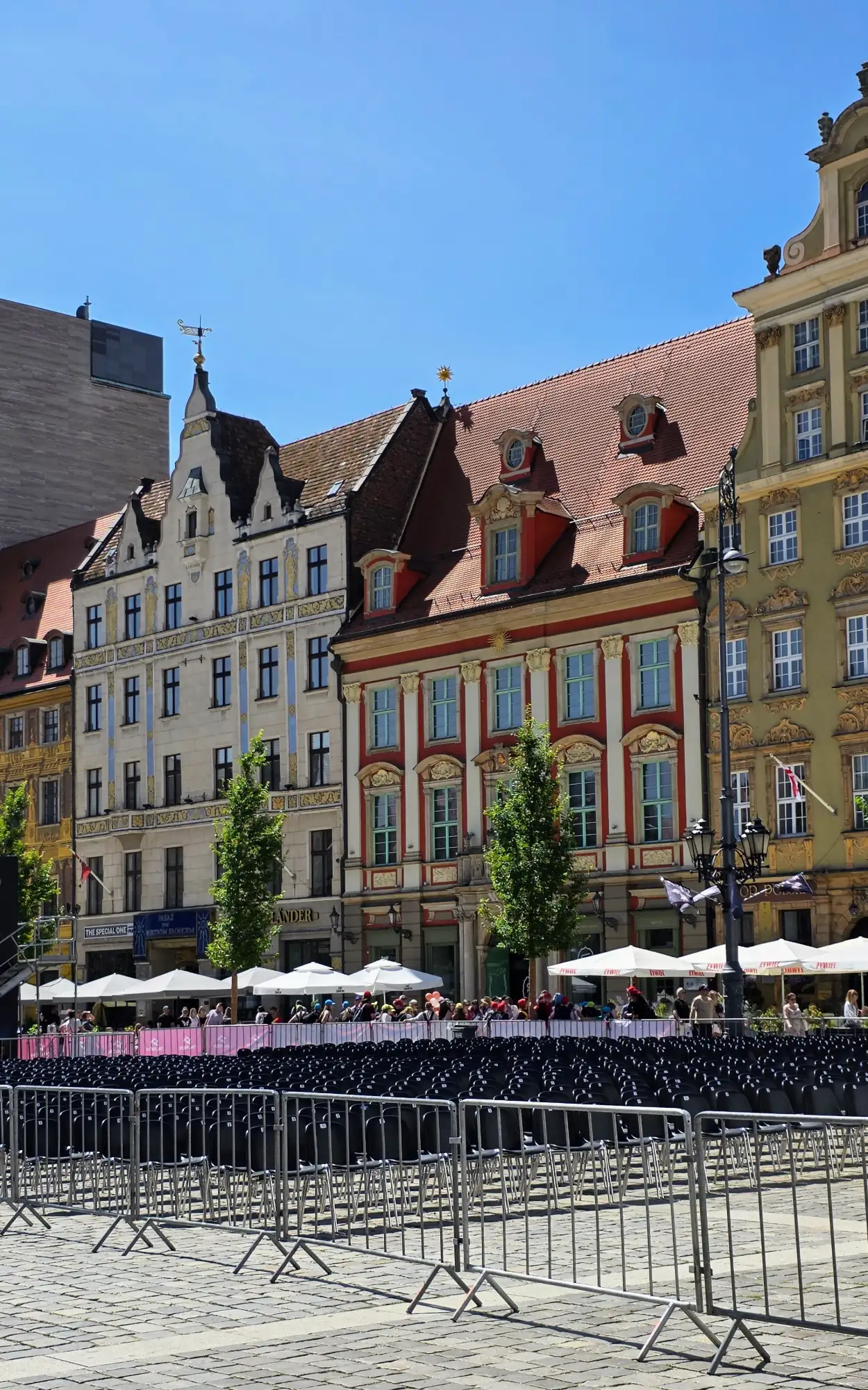 Colorful historic tenement houses on the Wrocław Market Square, with empty chairs set up for an event in the foreground.