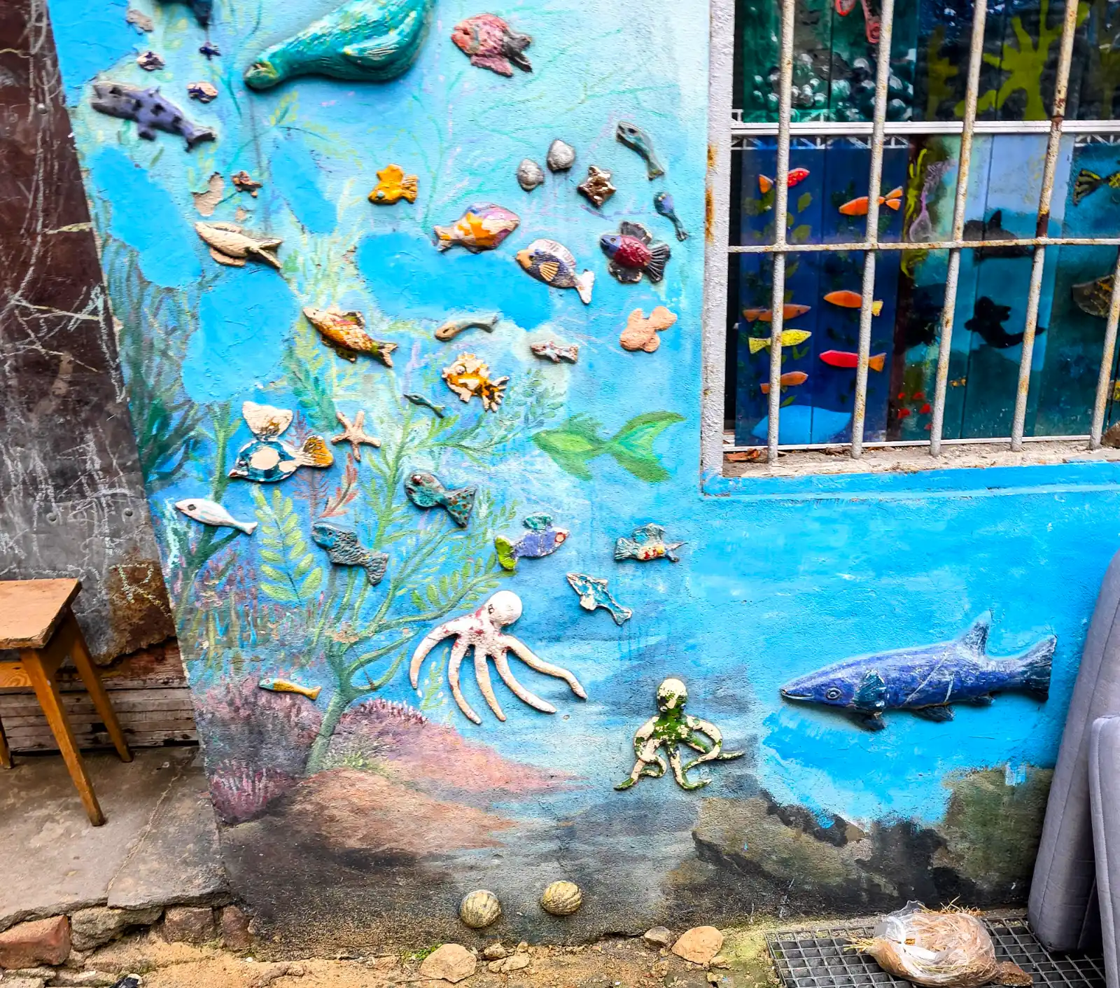 A bright blue wall mural with an underwater scene, decorated with 3D ceramic figures of fish and an octopus.