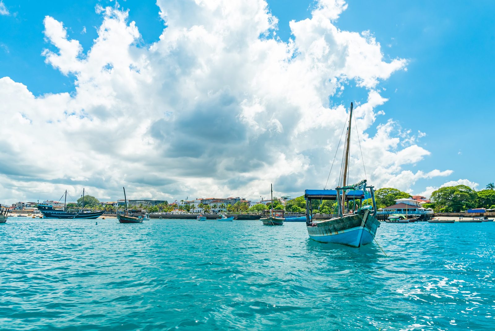 A view of boats on a turquoise body of water under a partly cloudy sky.