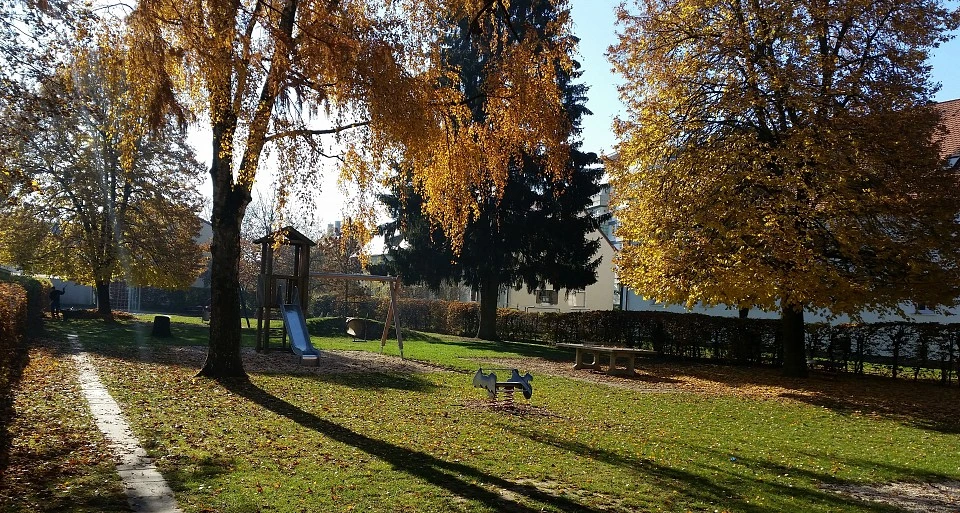 Herbstlich gefärbte Bäume auf der Grünanlage mit Spielplatz an der Franz-Xaver-Bauer-Straße